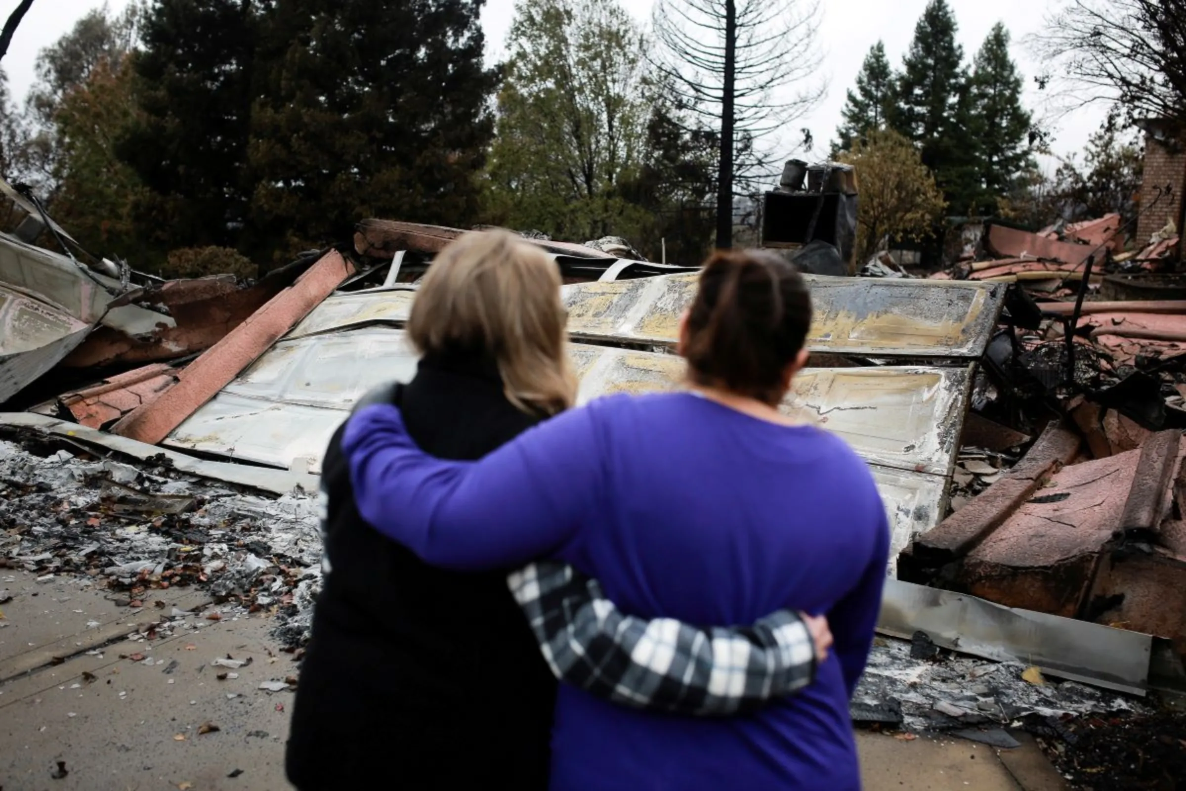 Neighbours comfort each other in front of the remains of a home after returning for the first time since the Camp Fire in Paradise, California, U.S. November 22, 2018. REUTERS/Elijah Nouvelage