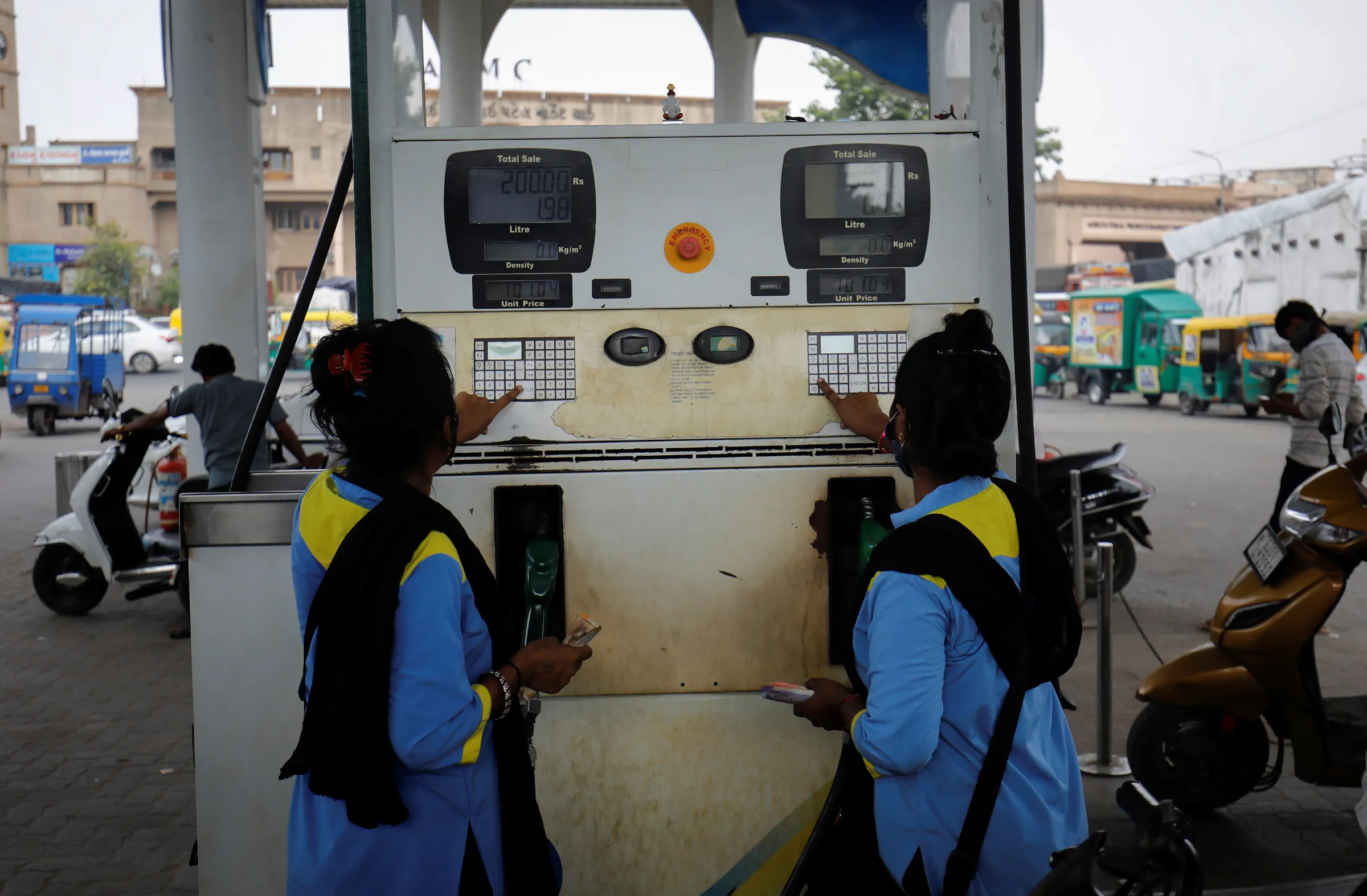 Workers enter the amount into a fuel pump machine before filling up the vehicles at a petrol station in Ahmedabad, India, October 11, 2021. REUTERS/Amit Dave