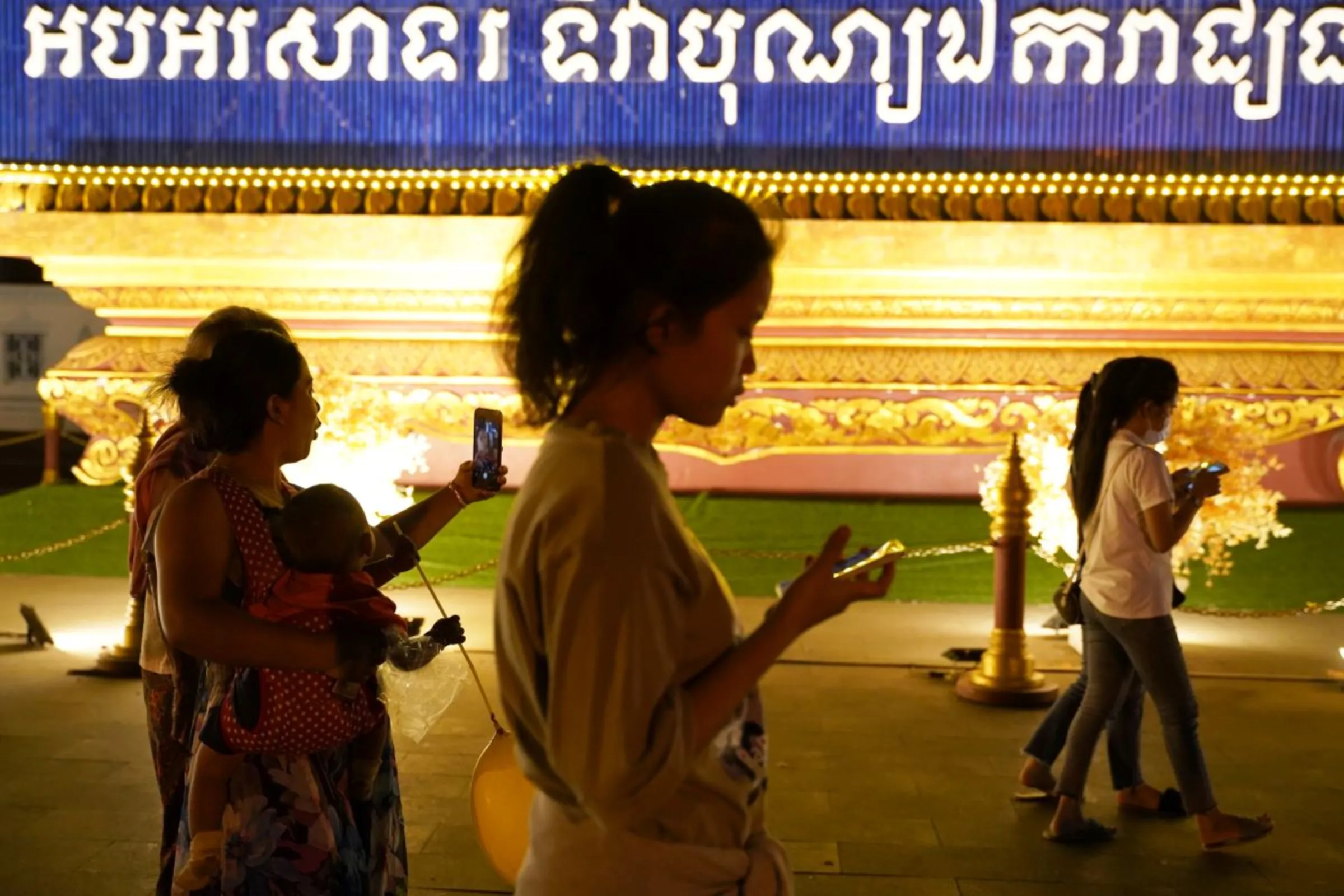 People walk using their mobiles phones in Phnom Penh, Cambodia, February 18, 2021. REUTERS/Cindy Liu