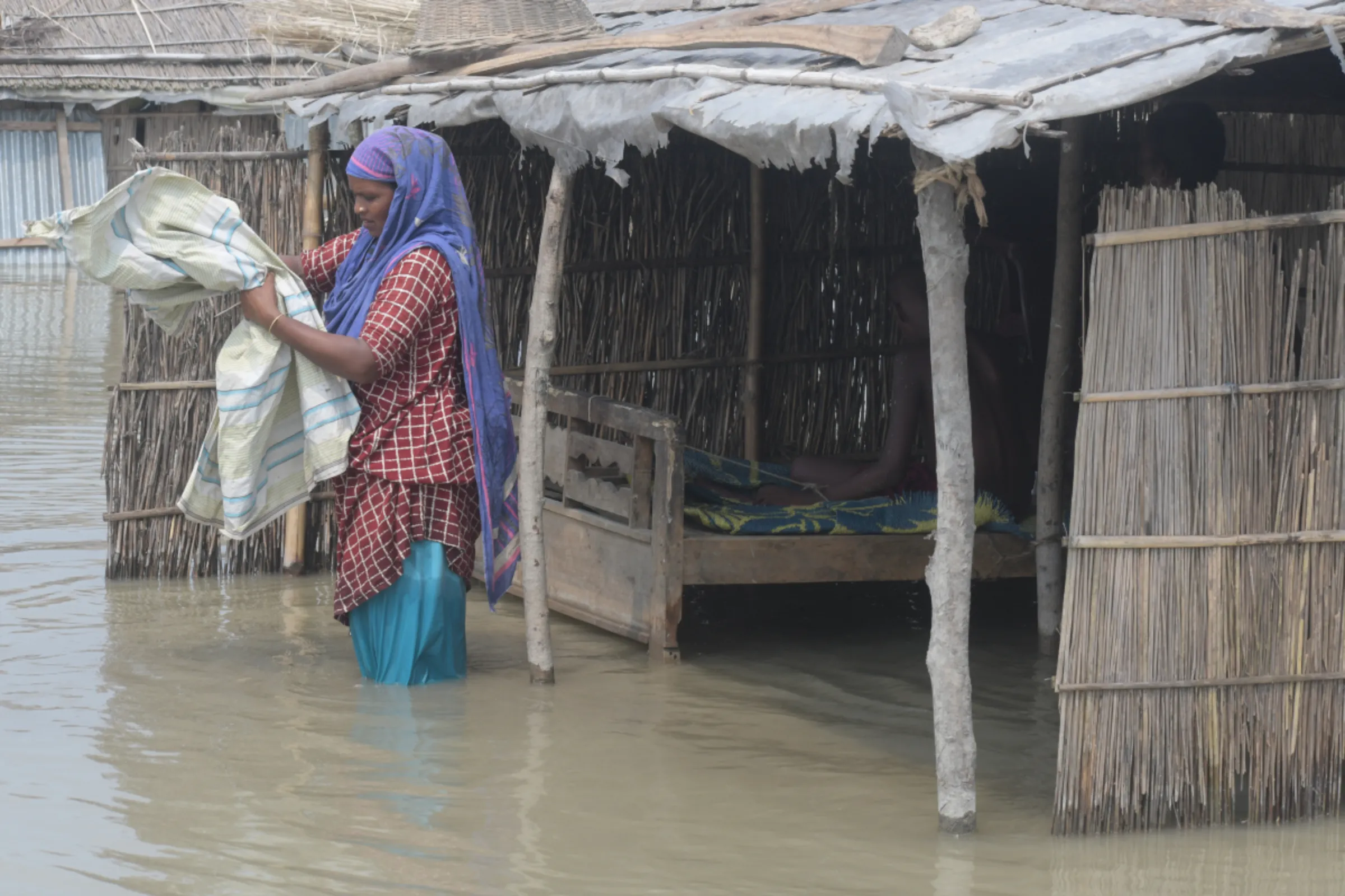 A woman wades in floodwater outside her home in Bogura, northern Bangladesh, September 17, 2023