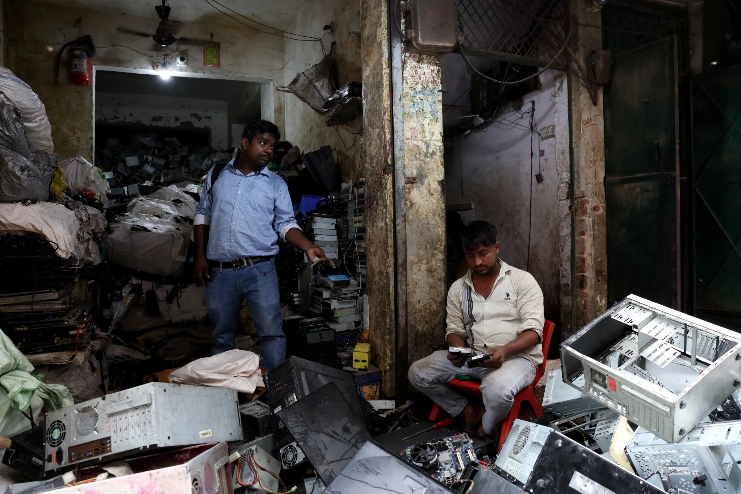 A man pays cash as he buys second hand hard disks from a scrap dealer at an e-waste market in New Delhi, India, July 29, 2025. REUTERS/Bhawika Chhabra