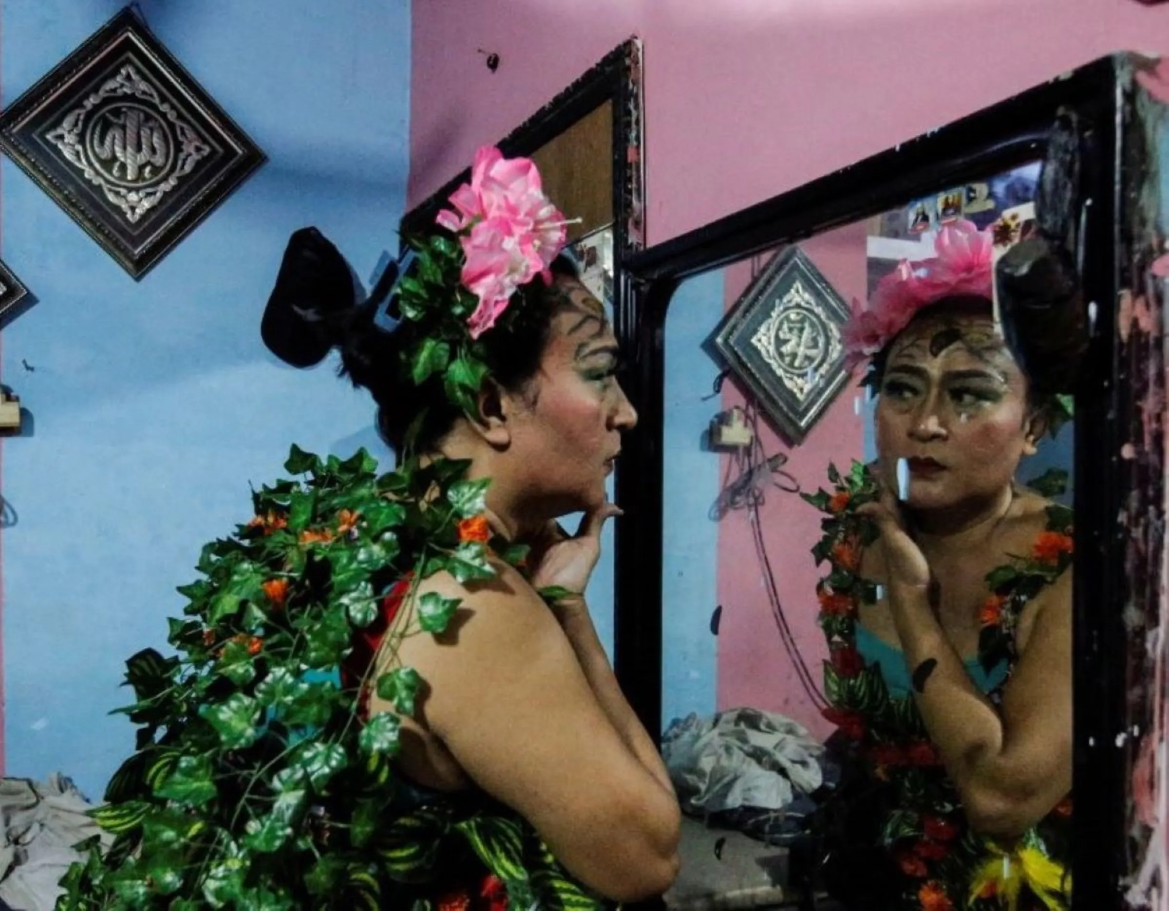 Nuke Herawati, 43, a trans woman who wears a recycled material dress to bring awareness to LGBT rights and environmental protection, looks in the mirror before a Trans Super Heroes fashion show at a traditional market in Jakarta, Indonesia, December 17, 2023. REUTERS/Ajeng Dinar Ulfiana