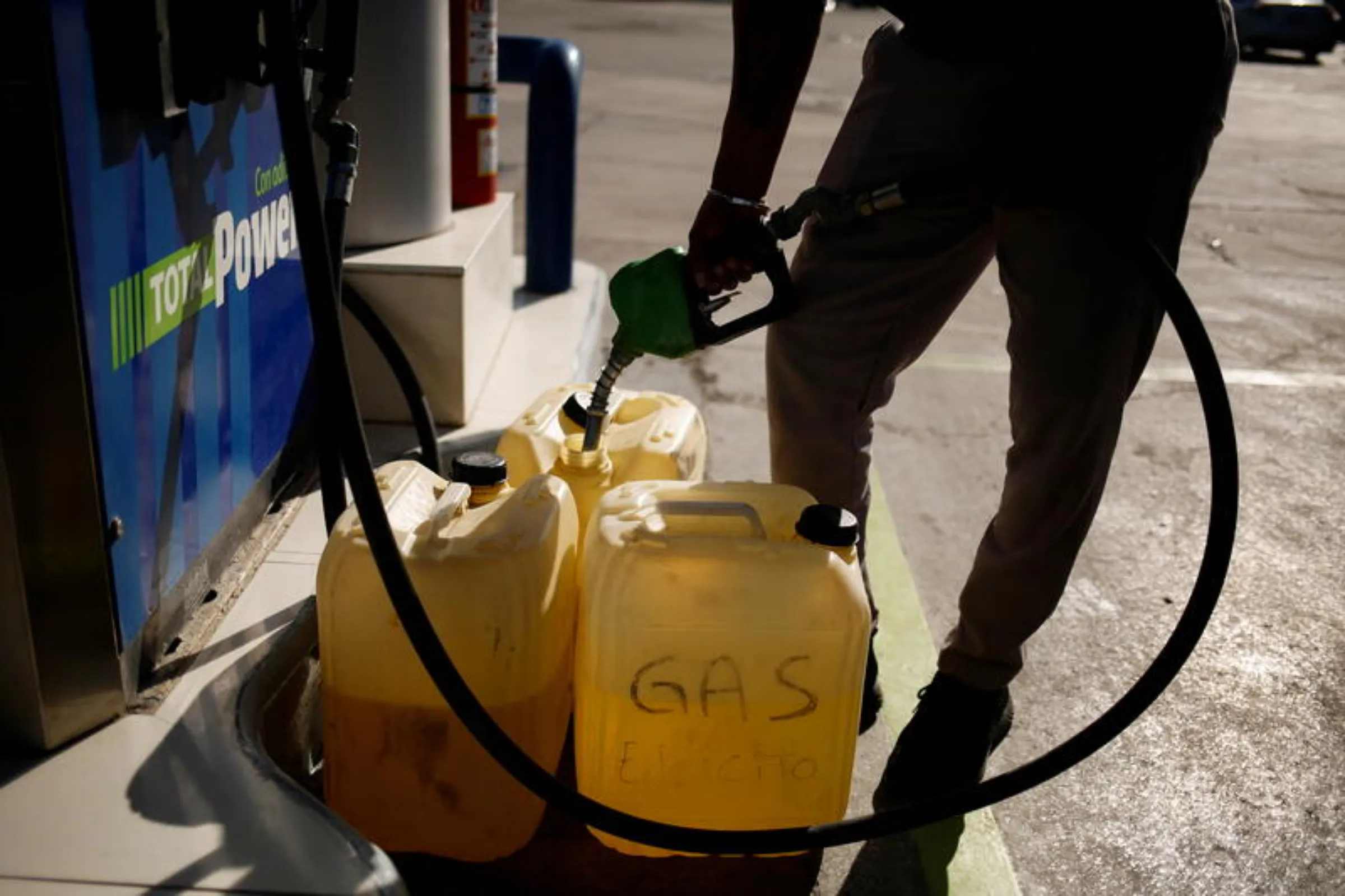 A man fills plastic containers with gasoline at a service station after Mexico suspended the gasoline subsidy along the U.S. border, in Ciudad Juarez, Mexico, April 4, 2022. REUTERS/Jose Luis Gonzalez