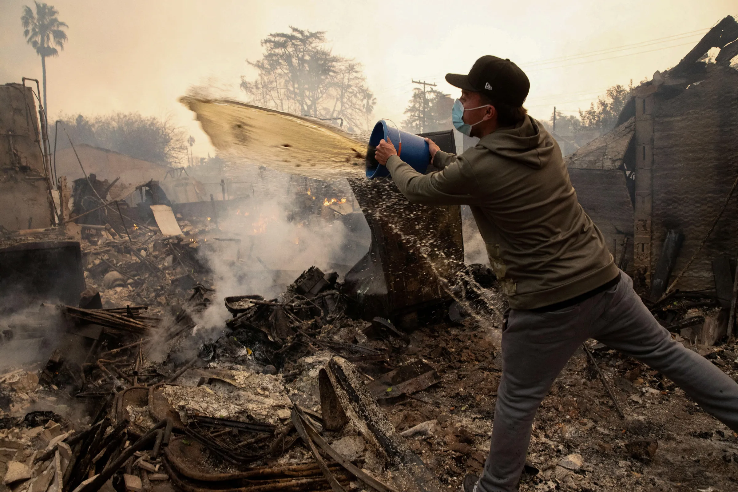A resident uses buckets of water following fires in Altadena, California, U.S. January 8, 2025. REUTERS/Zaydee Sanchez