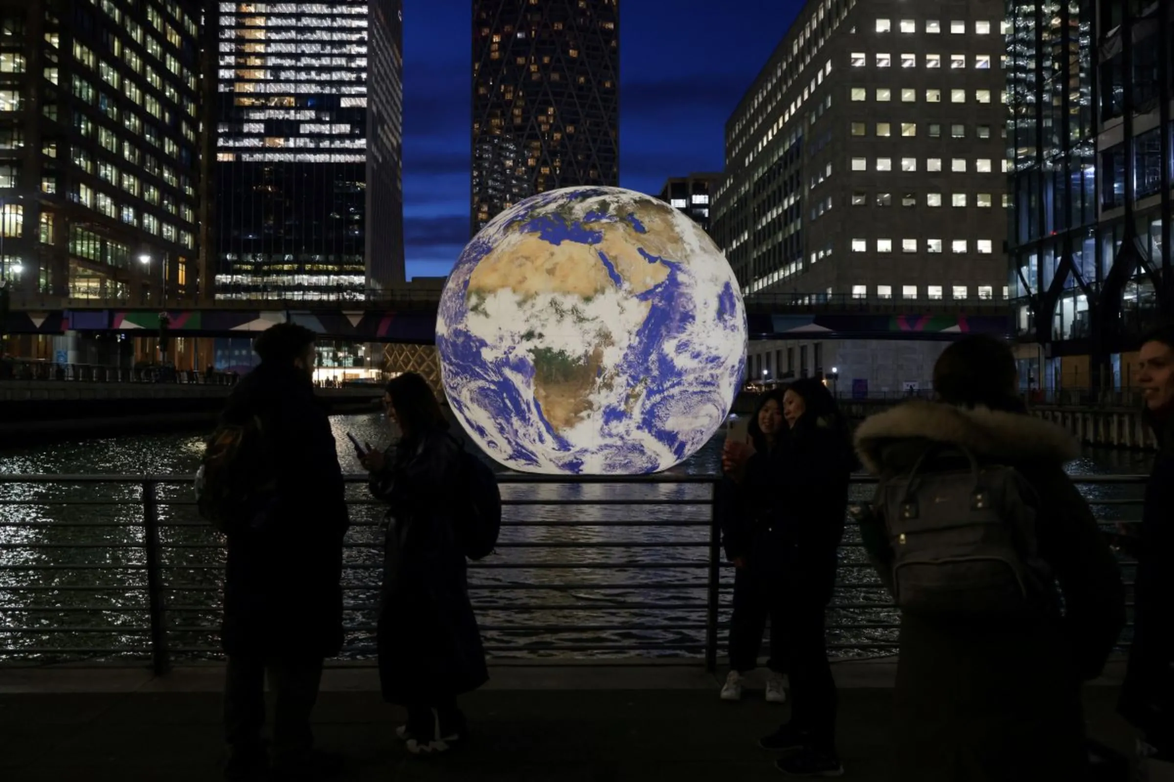 People look at Luke Jerram's 'Floating Earth', an installation as part of the Canary Wharf Winter Lights festival in the financial district in London, Britain, January 17, 2023