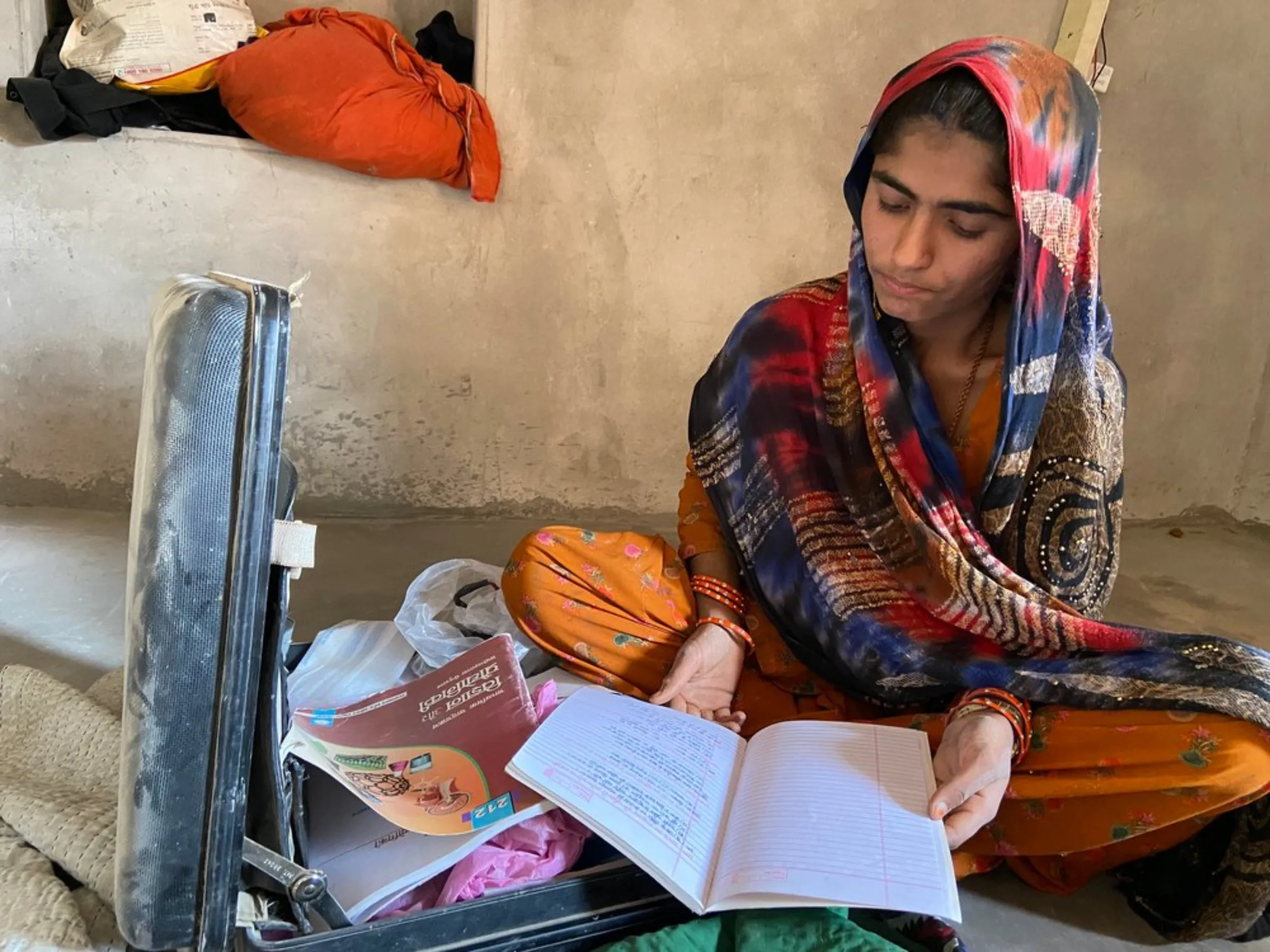 Teenager Hira Bano pulls out her books from a briefcase in her house near Bhadla Solar Park, Rajasthan, India, December 12, 2021