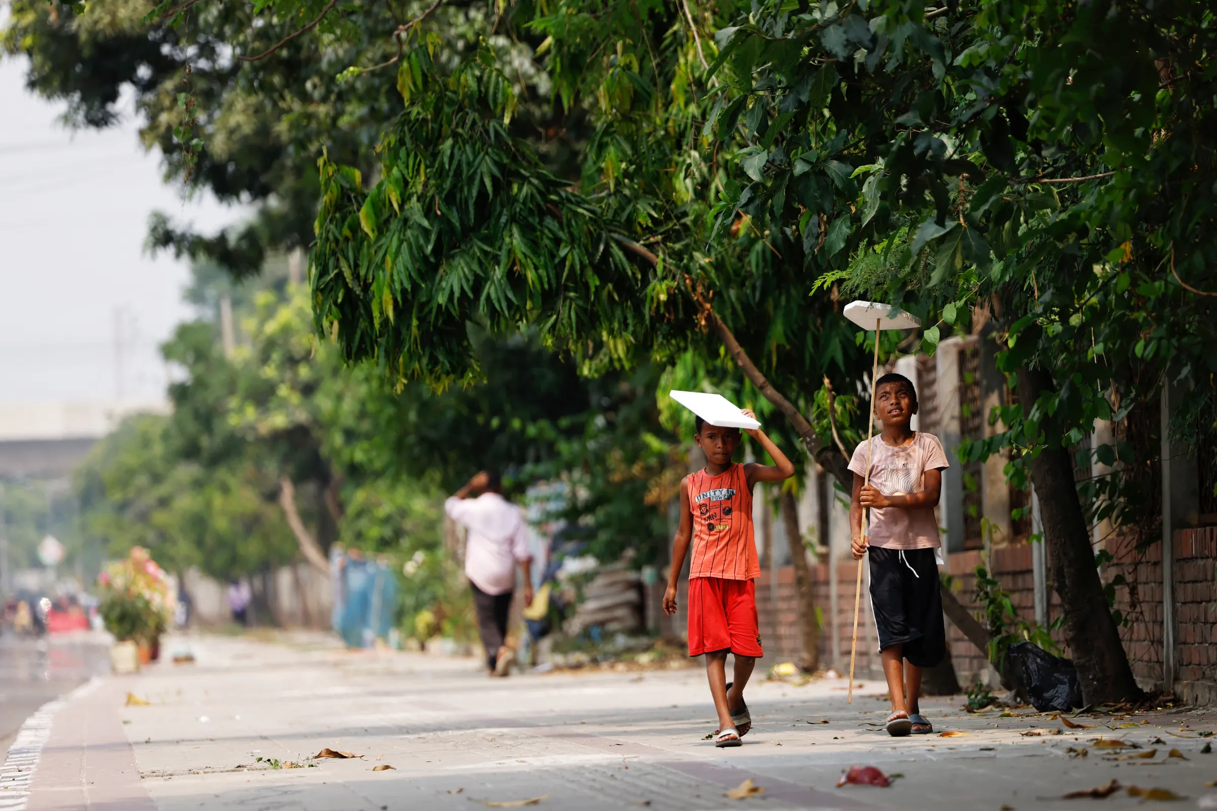 Children hold cork sheets to cover them from the sun while walking along a street during a countrywide heatwave in Dhaka, Bangladesh, April 28, 2024. REUTERS/Mohammad Ponir Hossain