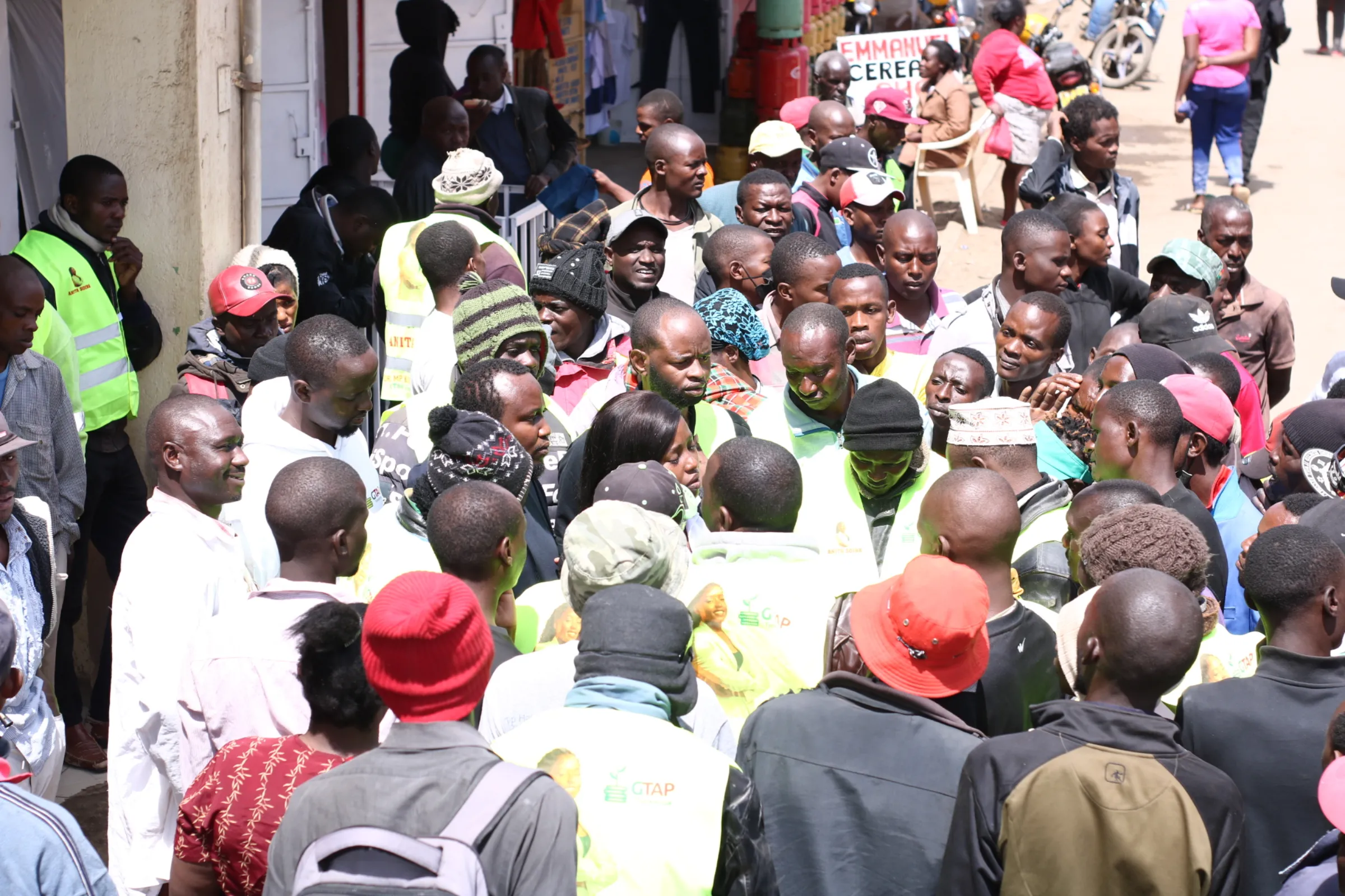 A crowd of people surround a woman on a busy street