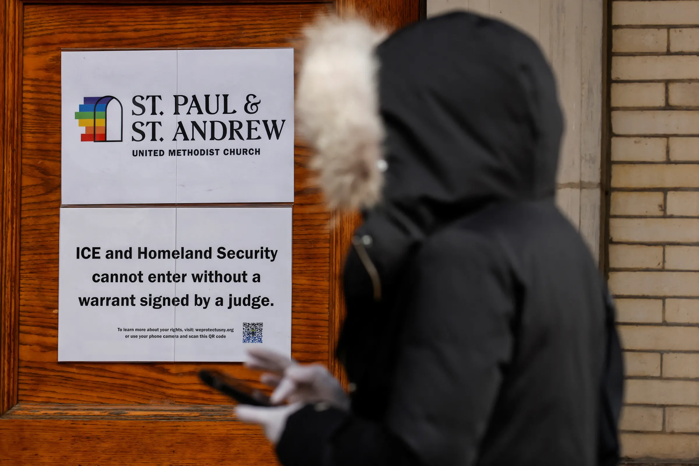A sign prohibiting ICE and Homeland Security from entering without a warrant is posted on a door at St. Paul and St. Andrew United Methodist Church while a person waits to go inside to the church in New York City, U.S., January 23, 2025. REUTERS/Eduardo Munoz