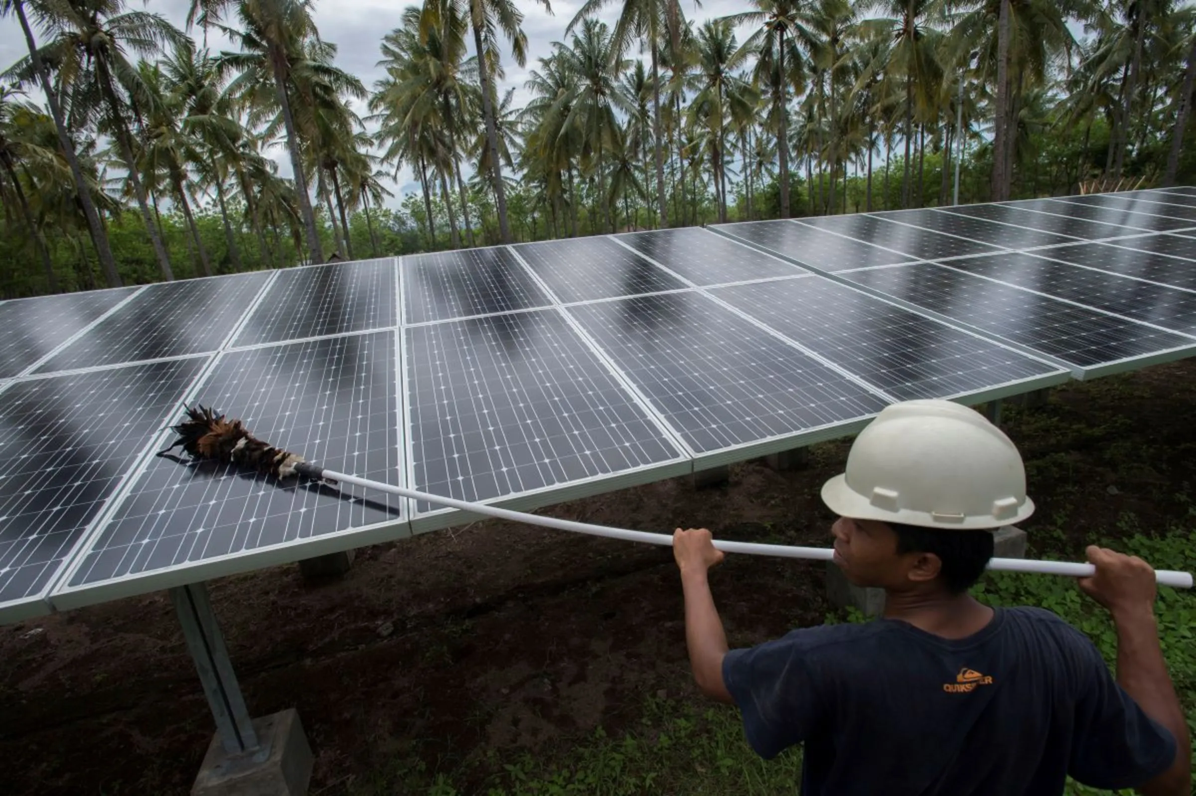 An employee of PT Perusahaan Listrik Negara (PLN) cleans the surface of solar panels at a solar power generation plant in Gili Meno island, Indonesia, December 9, 2014