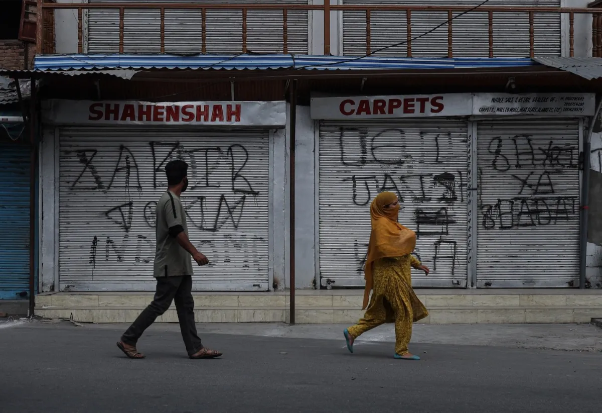 Residents walk past shuttered shops in downtown Srinagar, India. ‎August ‎5, 2021. Thomson Reuters Foundation/Mehran Bhat