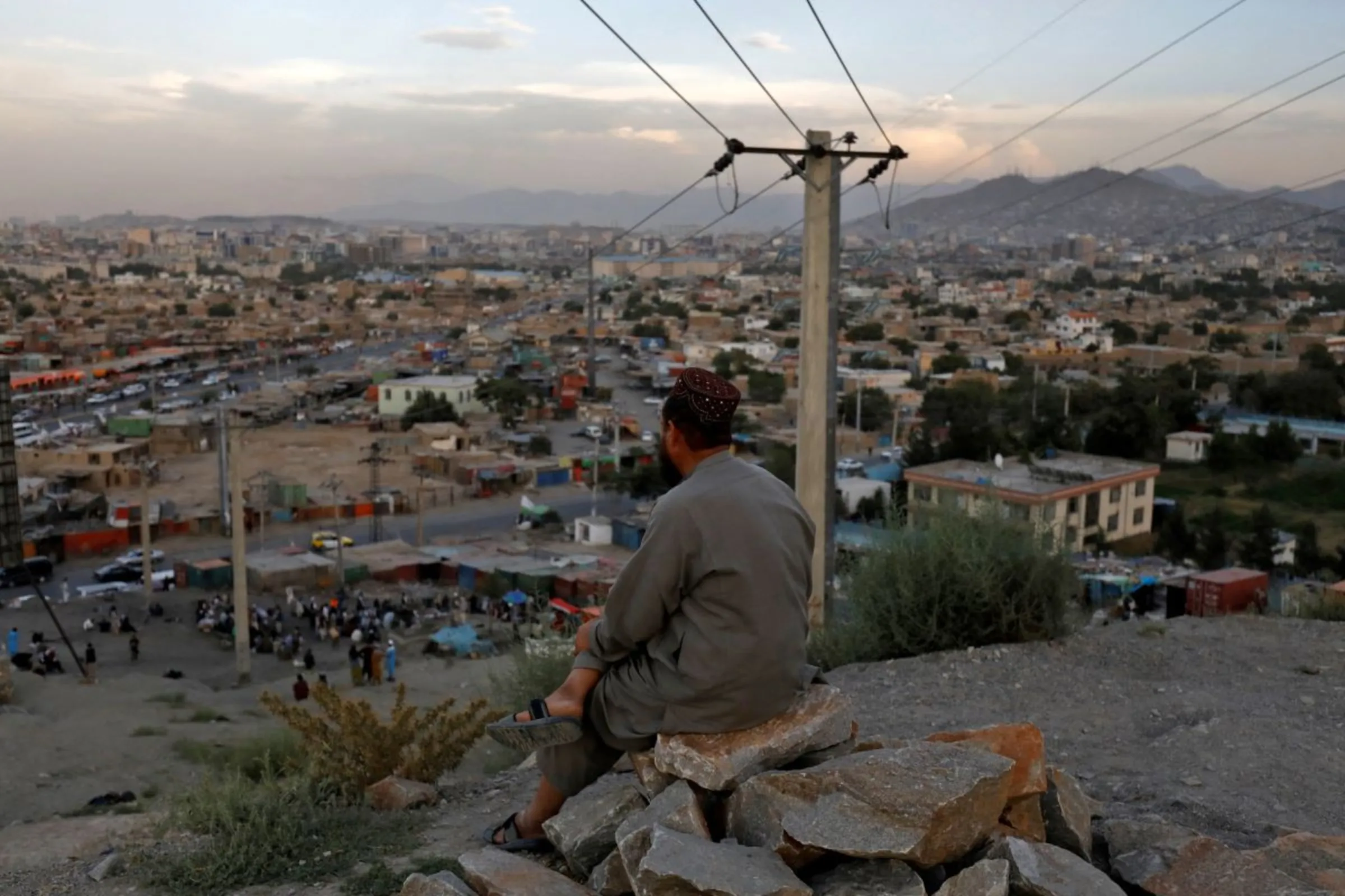 An Afghan man sits on a hilltop overlooking in Kabul, Afghanistan, August 5, 2022. REUTERS/Ali Khara