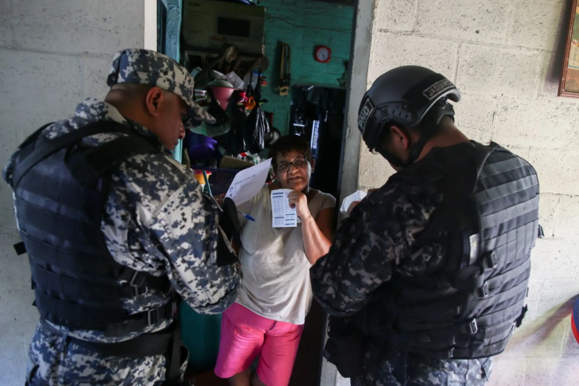 Policemen check the documents of a woman during an anti-gang patrol at Las Margaritas neighborhood following a year-long state of emergency against gangs, in Soyapango, El Salvador March 24, 2023. REUTERS/Jose Cabezas