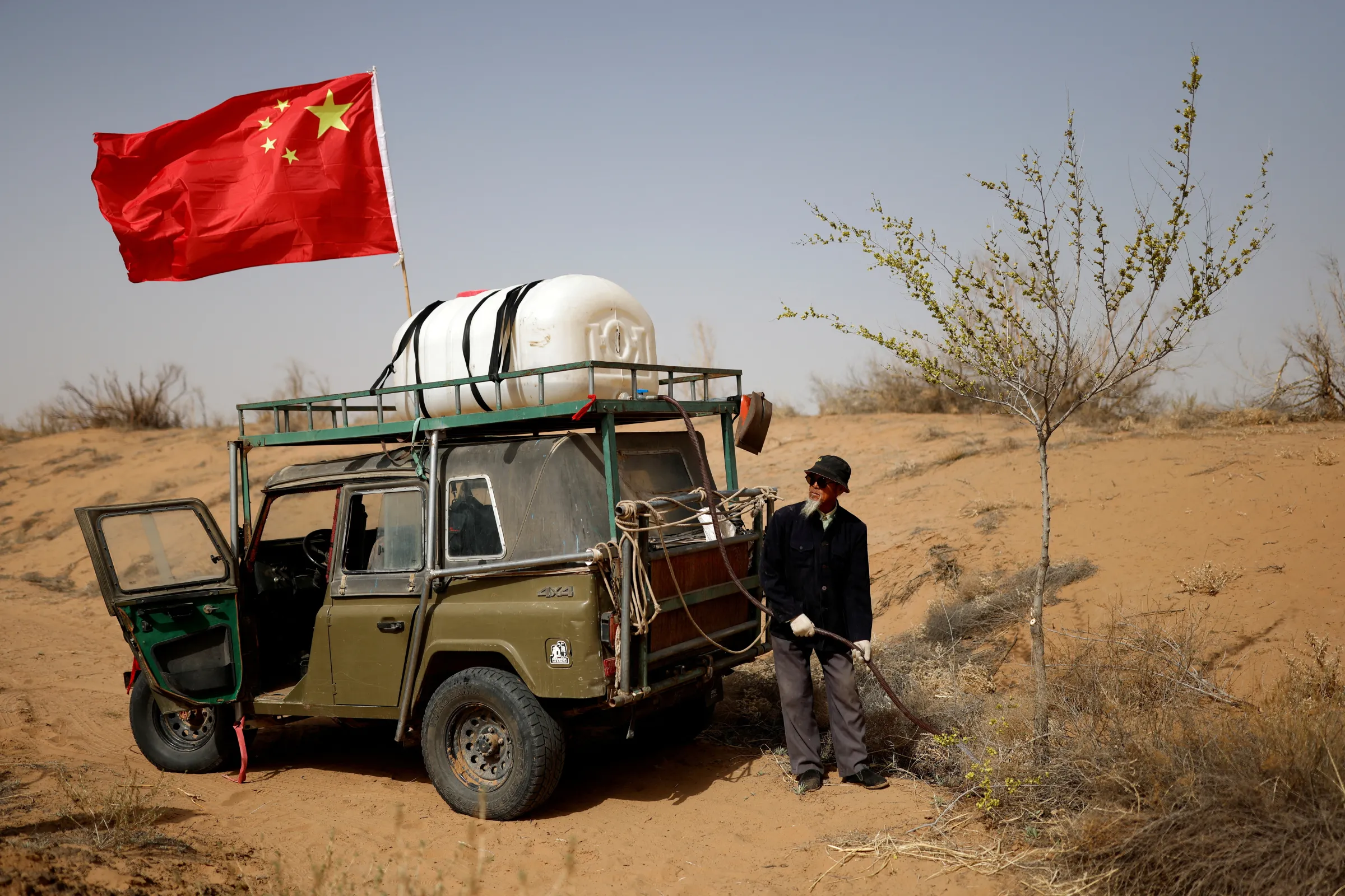 A man waters a tree planted on the edge of the Gobi desert on the outskirts of Wuwei, Gansu province, China, April 15, 2021.  REUTERS/Carlos Garcia Rawlins