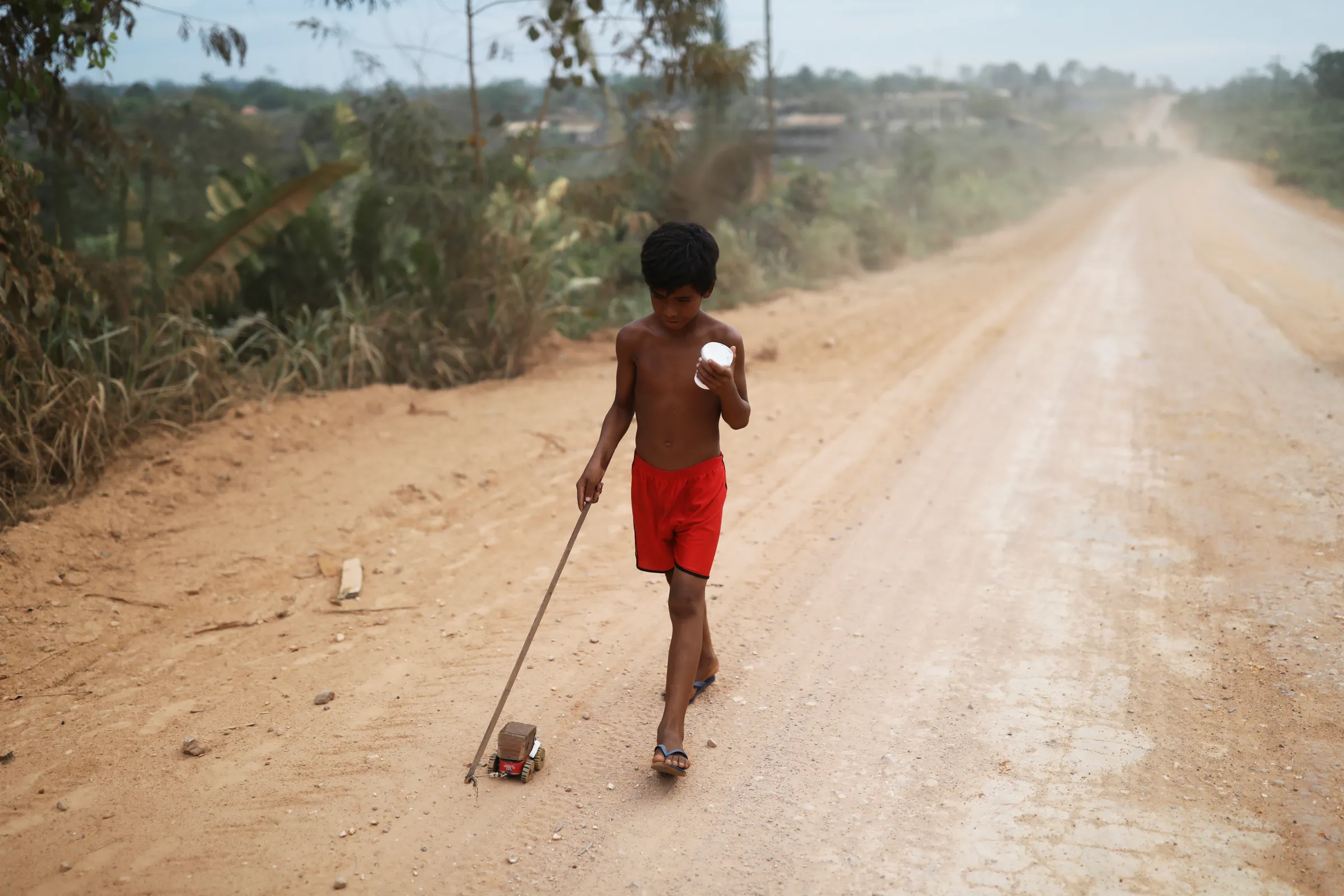 A boy plays with a wooden toy tractor on Trans-Amazonian Highway near the city of Altamira, Para state, Brazil, August 27, 2019. REUTERS/Nacho Doce