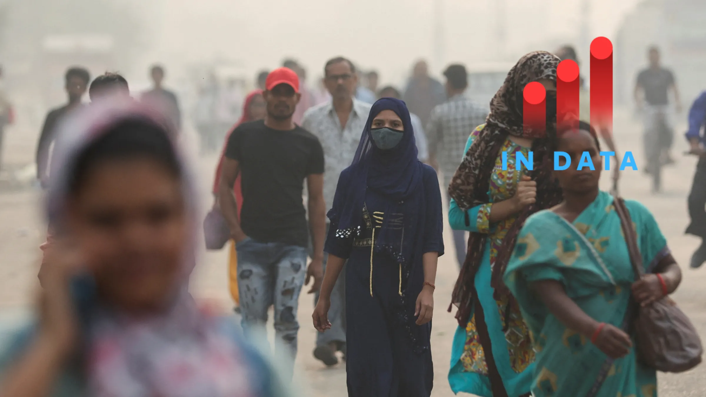 A woman with a facemask and other people walk amidst the morning smog in New Delhi, India, November 8, 2023. REUTERS/Anushree Fadnavis