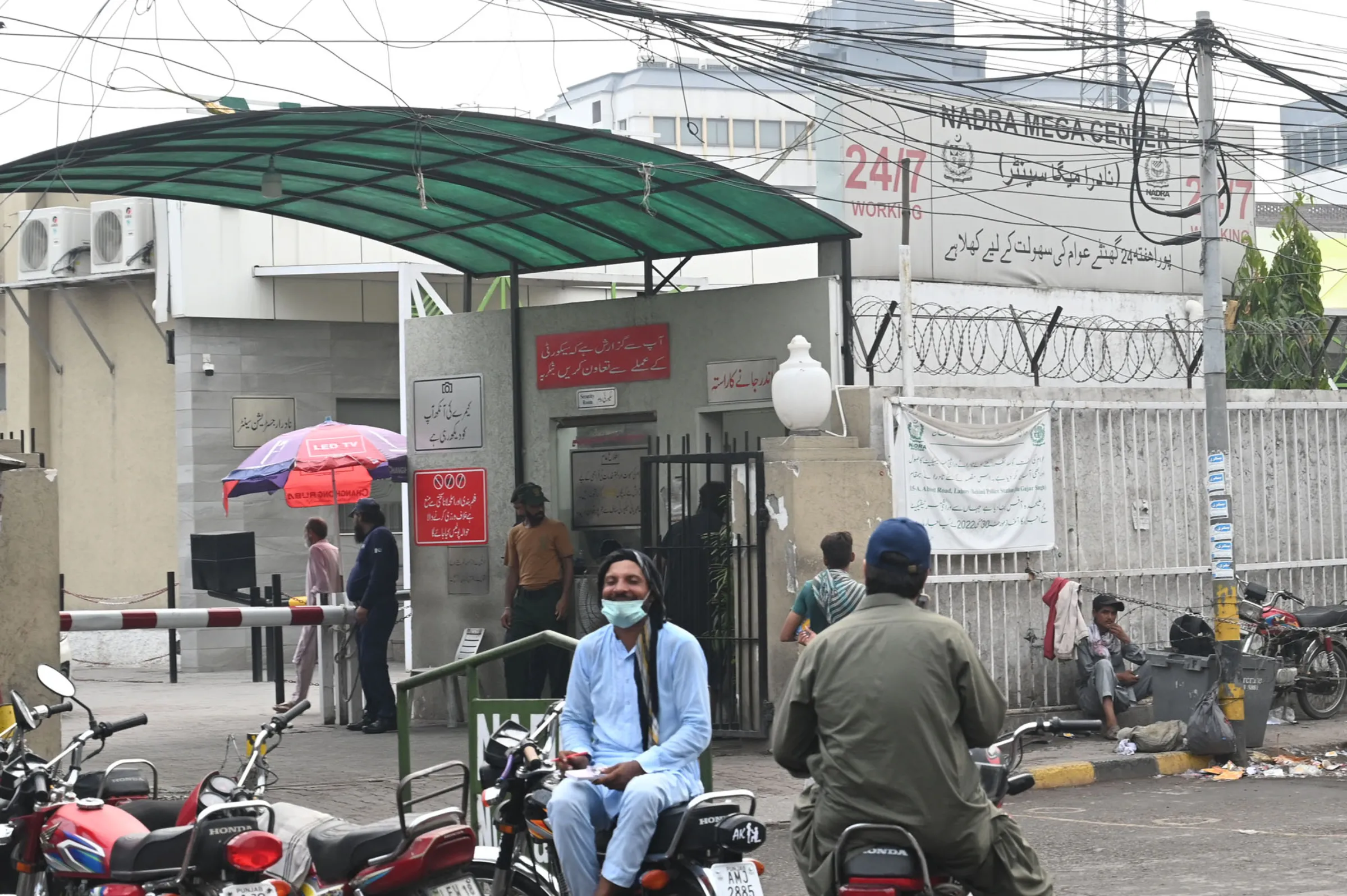 People wait outside a National Database and Registration Authority (NADRA) centre in Lahore, Pakistan