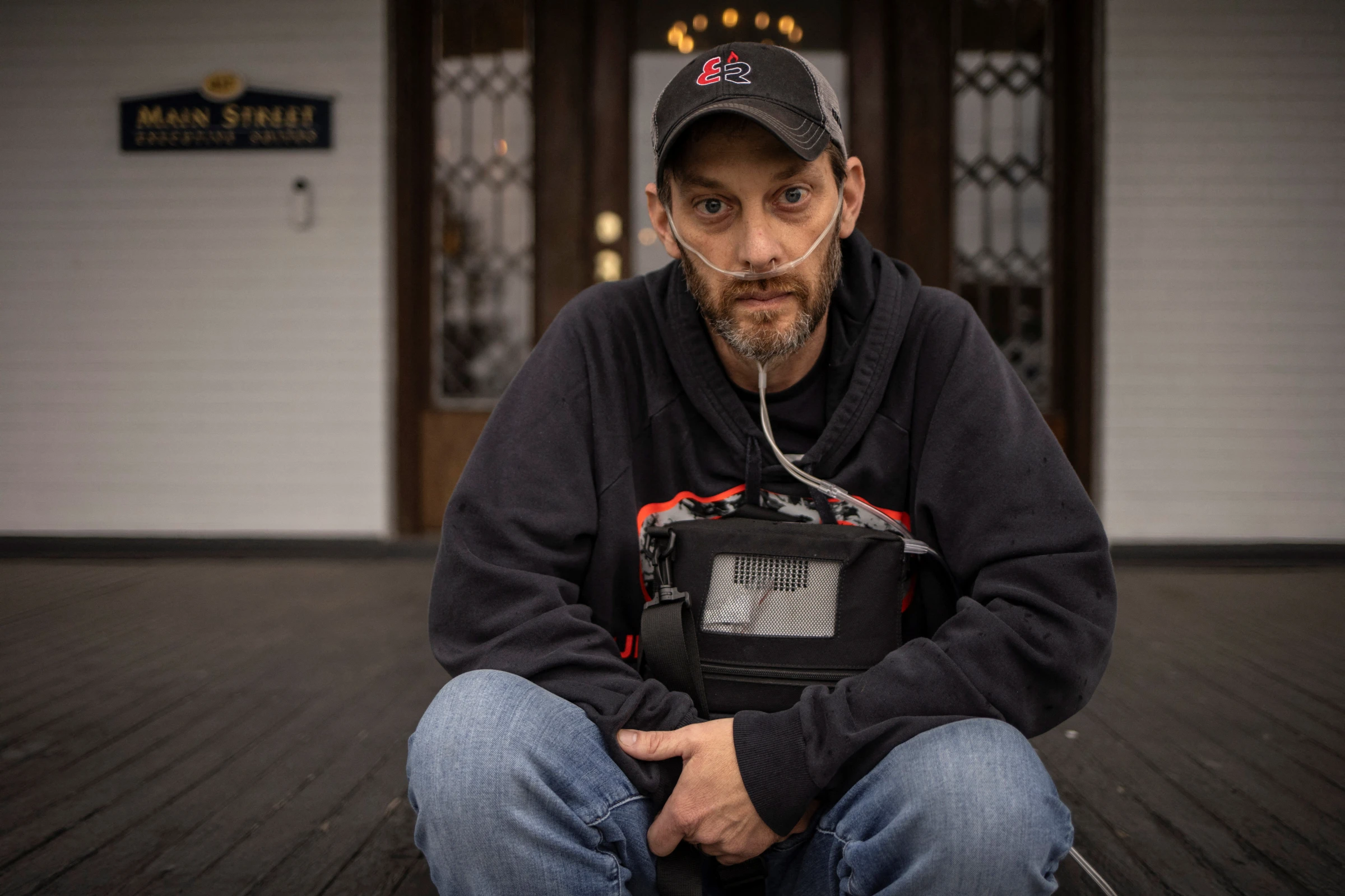 An underground coal miner holds his portable oxygen concentrator while sitting outside a law office in Oak Hill, West Virginia, U.S., April 10, 2025. REUTERS/Adrees Latif