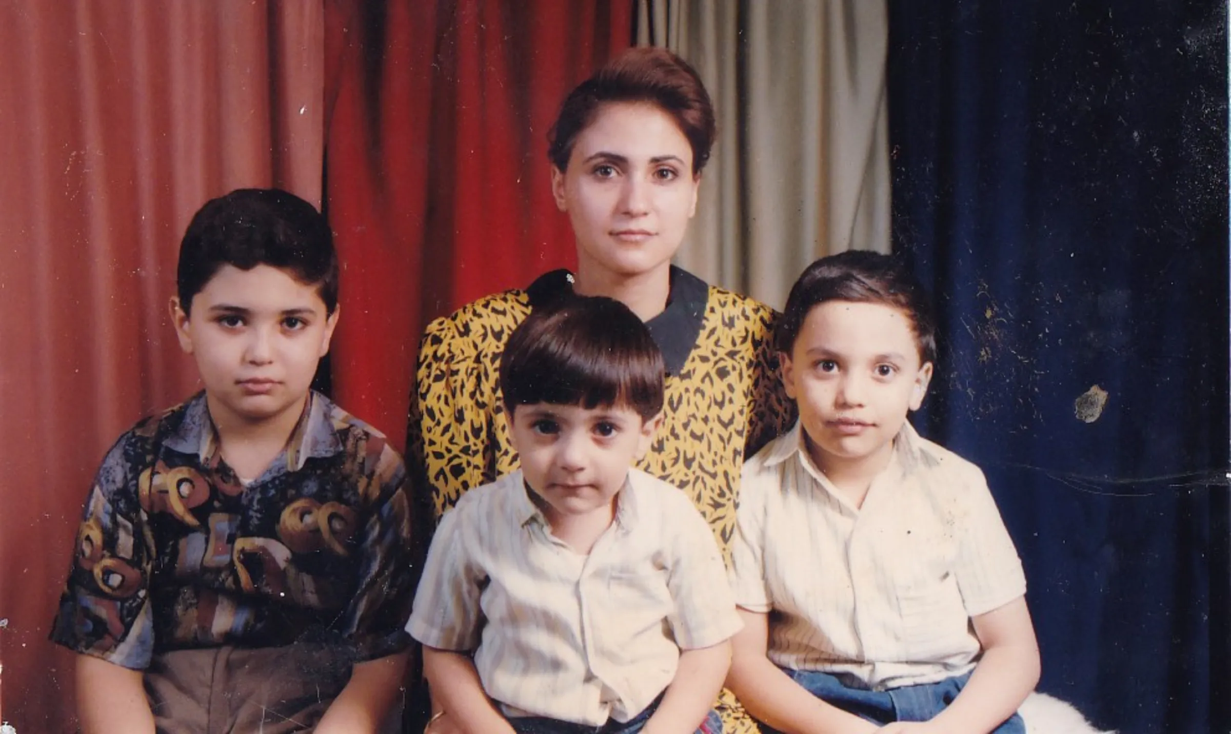 Three children sit in a row in front of their mother