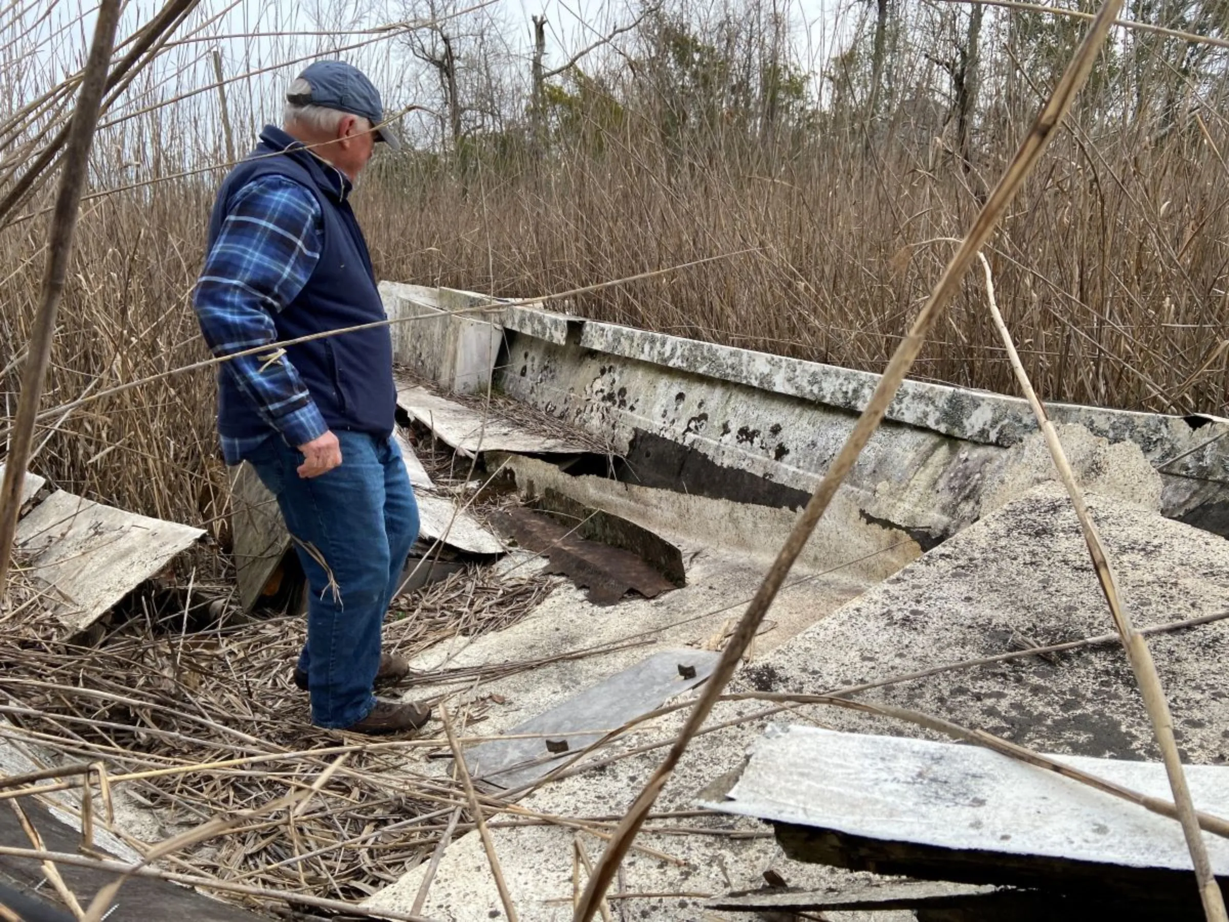 Robert Parr, former oceanographer, examines a wrecked boat at a site across the Cape Fear River from downtown Wilmington in North Carolina, USA, February 29, 2024. Thomson Reuters Foundation/David Sherfinski