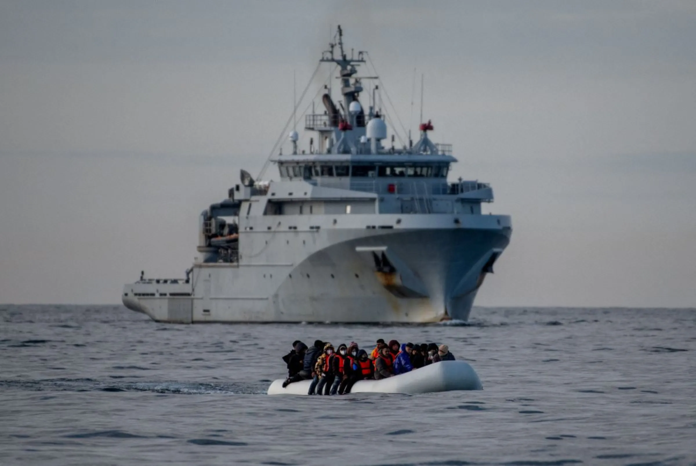 An inflatable dinghy carrying migrants passes a French navy vessel as it heads towards England in the English Channel, Britain, May 4, 2024. REUTERS/Chris J. Ratcliffe