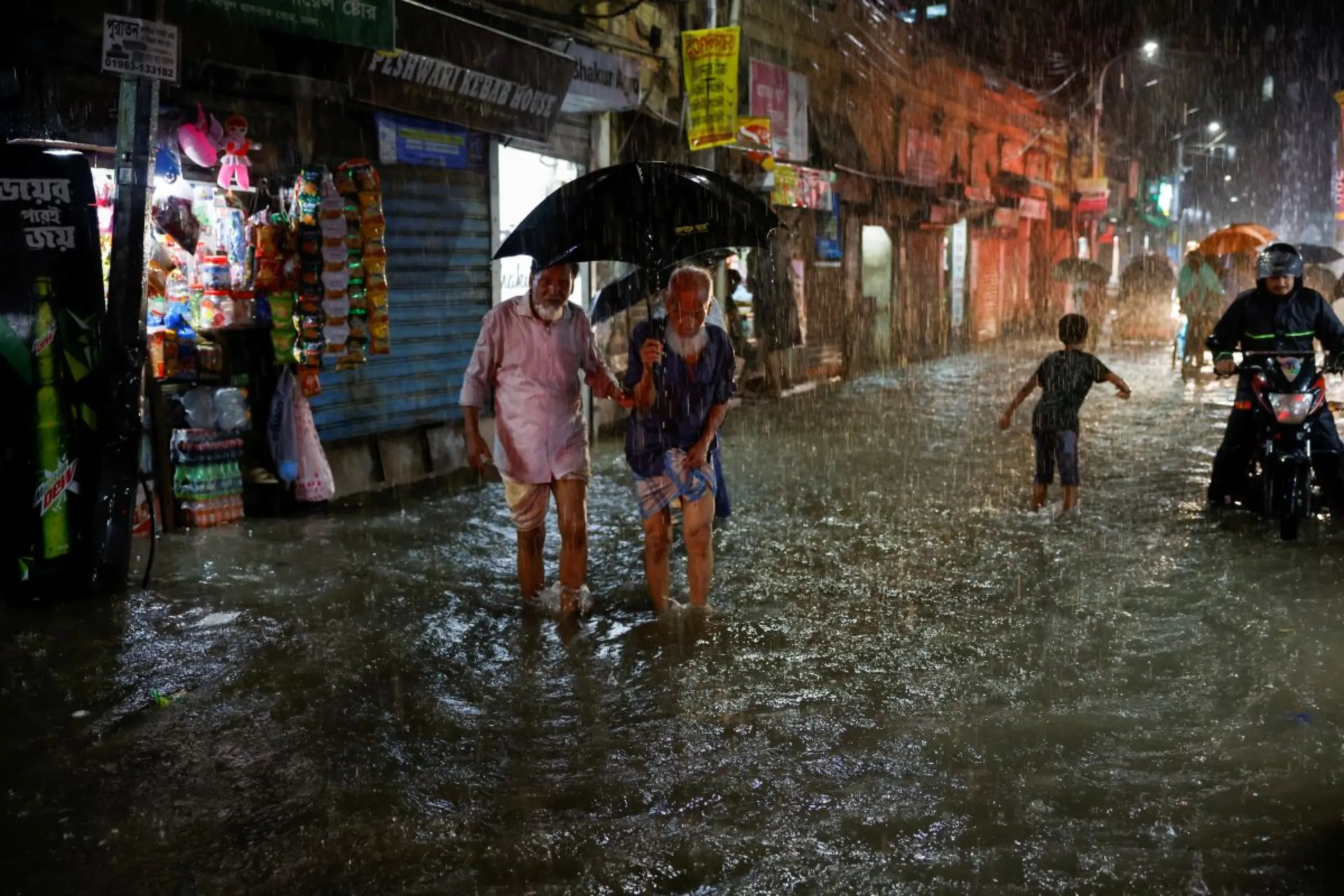 People wade through a flooded street amid continuous rain before the Cyclone Sitrang hits the country in Dhaka, Bangladesh, October 24, 2022. REUTERS/Mohammad Ponir Hossain