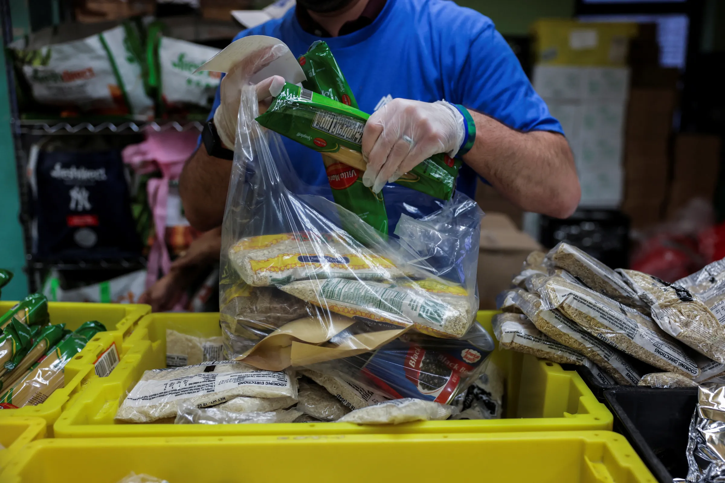 A volunteer puts food items into a bag at a New York Common Pantry distribution site, in the Bronx borough of New York City, U.S., August 20, 2025. REUTERS/Jeenah Moon