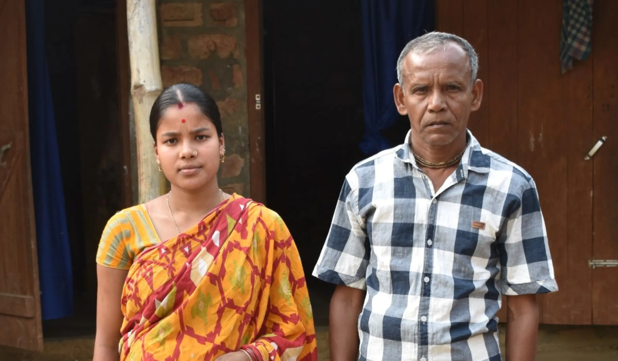 Teenage bride Pinku Das Sarkar, whose husband was arrested in the crackdown on child marriage, poses for a picture with her father-in-law Amulya Sarkar in front of her house in Radhanagar, India, February 28, 2023. Thomson Reuters Foundation/Biman Bora