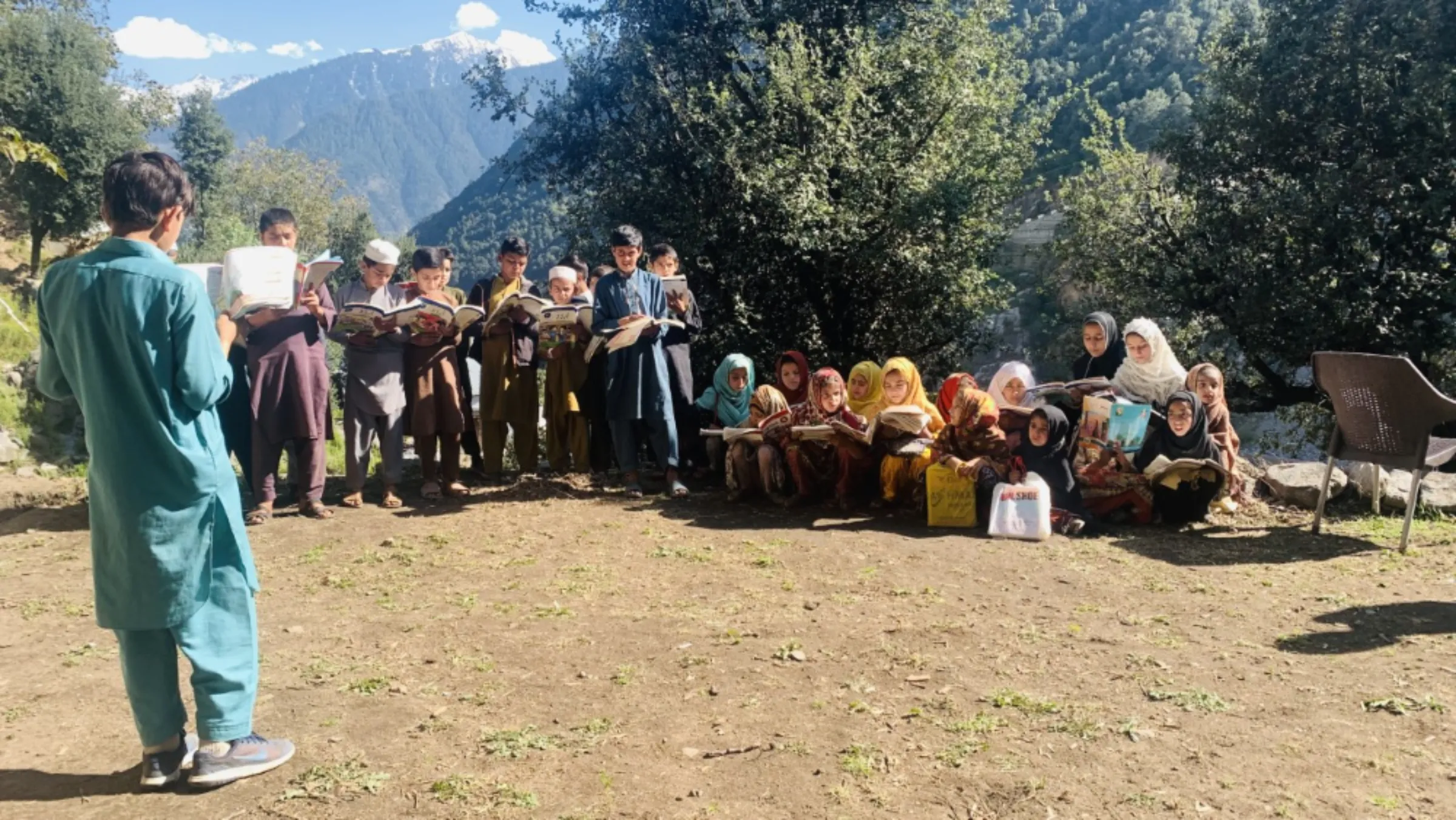 A student helps his classmates to read at a makeshfit school in Lagan Khar, a village in Swat district in Pakistan’s northwest Khyber Pakhtunkhwa province, October 24, 2022