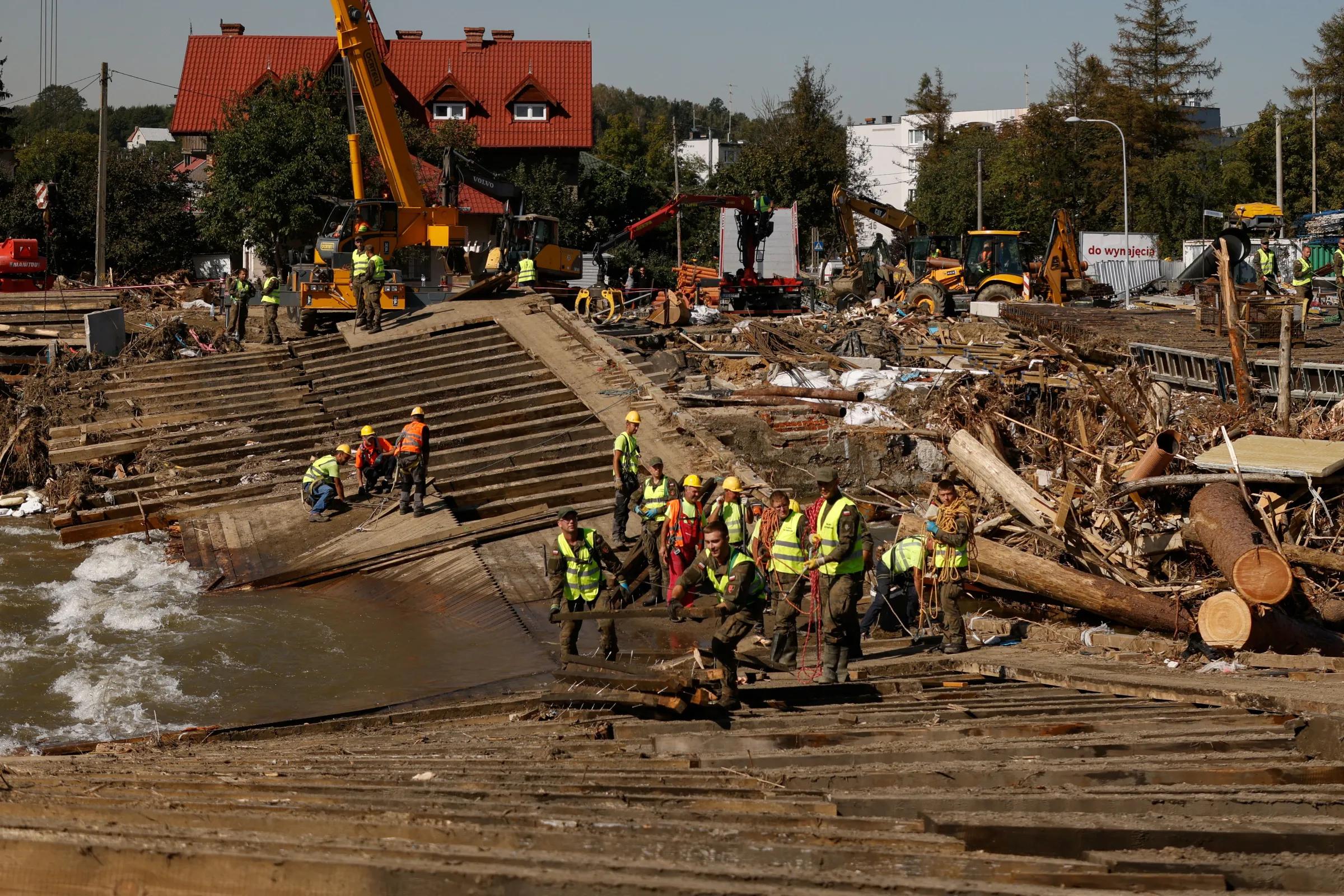 Workers and soldiers clean debris from a destroyed bridge in Glucholazy, Poland, September 20, 2024. REUTERS/Kuba Stezycki