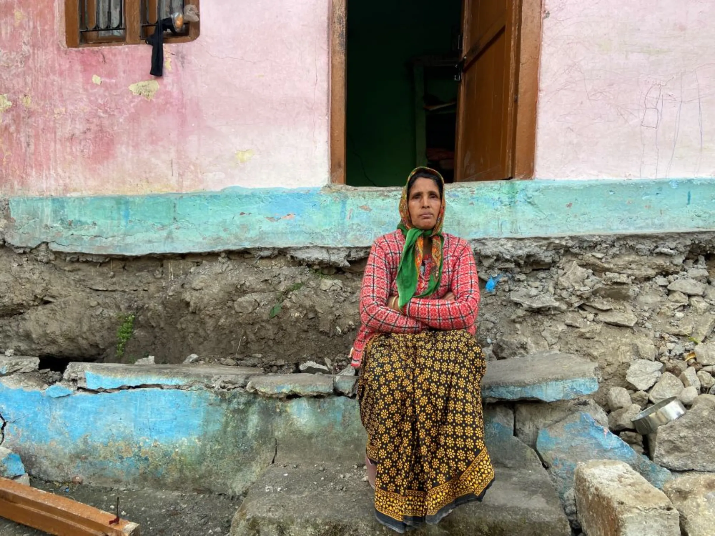 Farmer Rishi Devi sits outside her house that she evacuated in early January when massive cracks detached the house from its foundation in the Himalayan town of Joshimath, India, January 12, 2023