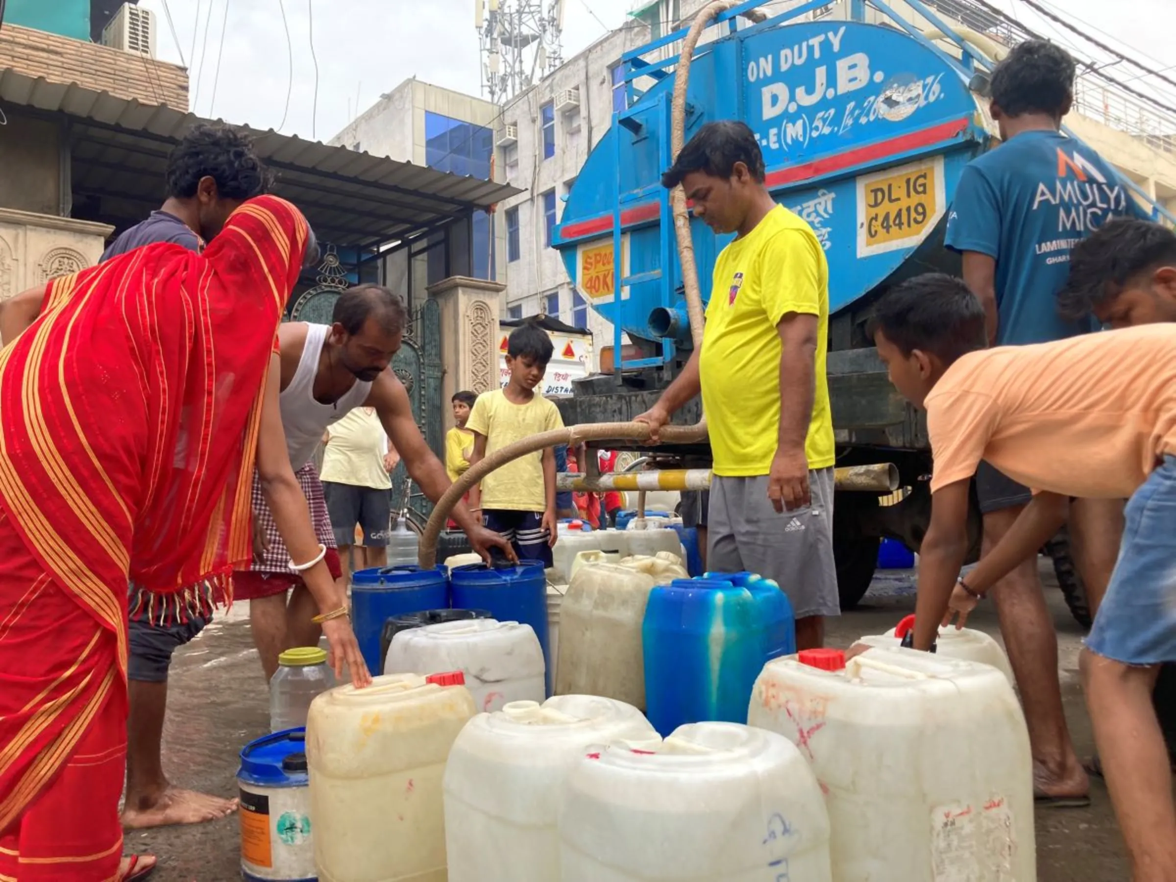 Residents at a low-income neighbourhood collect water from a tanker truck in Delhi, India, June, 22, 2024. Thomson Reuters Foundation/Annie Banerji