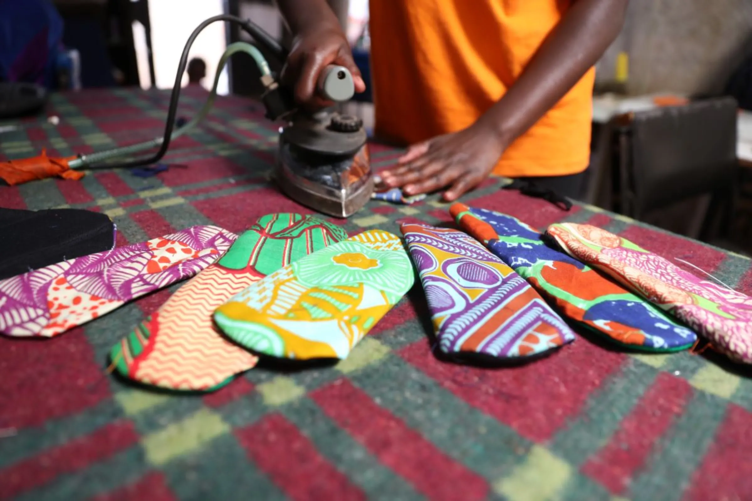 A woman irons a reuseable cloth sanitary pad at charity Amani Kibera in Kibera informal settlement in Nairobi, Kenya on April 15, 2023