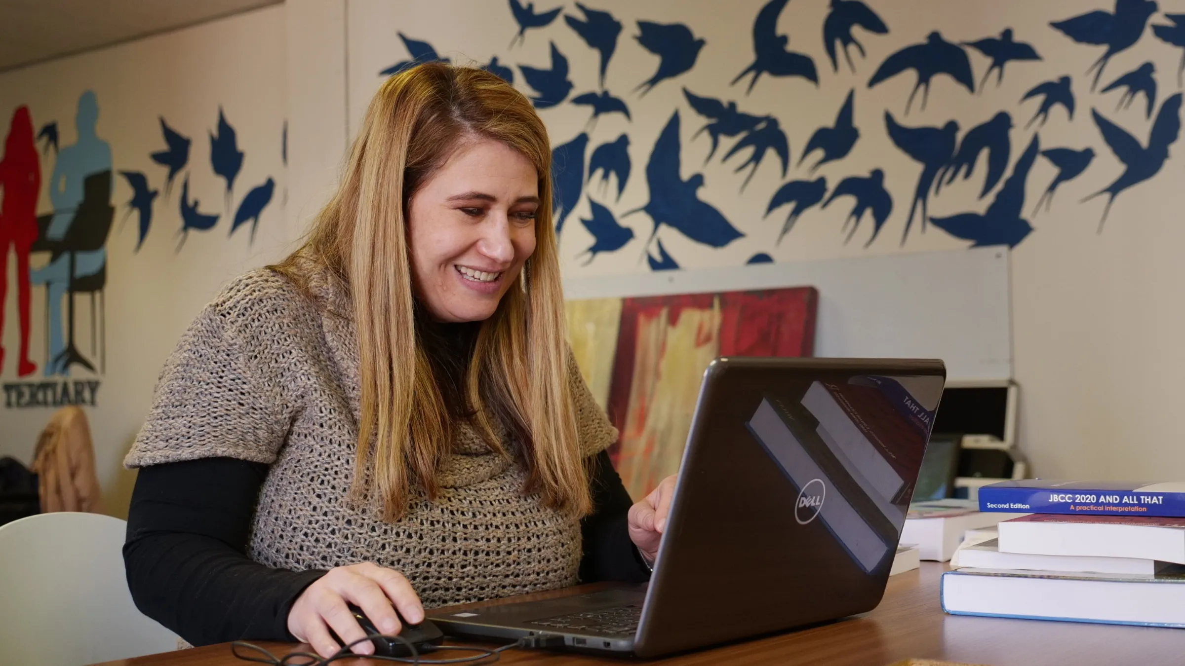 A woman works on a laptop at a desk