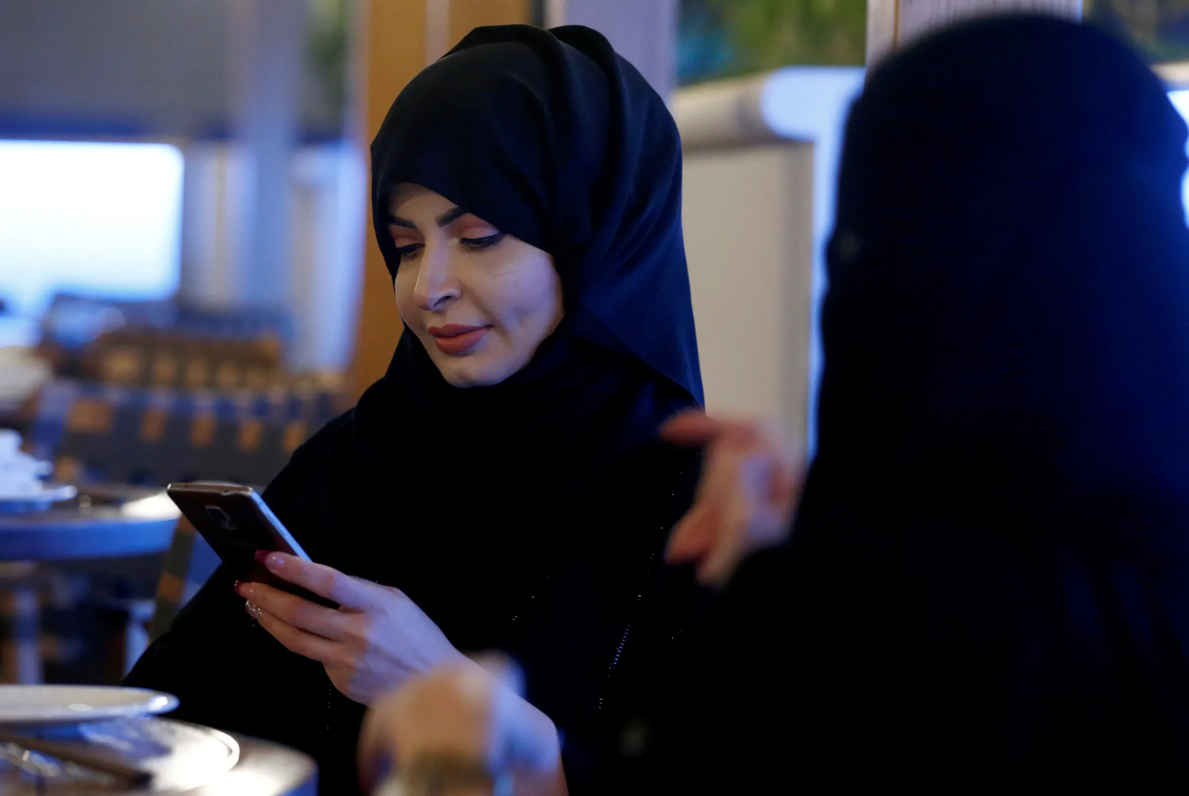 A woman uses her mobile phone in a cafe in Riyadh