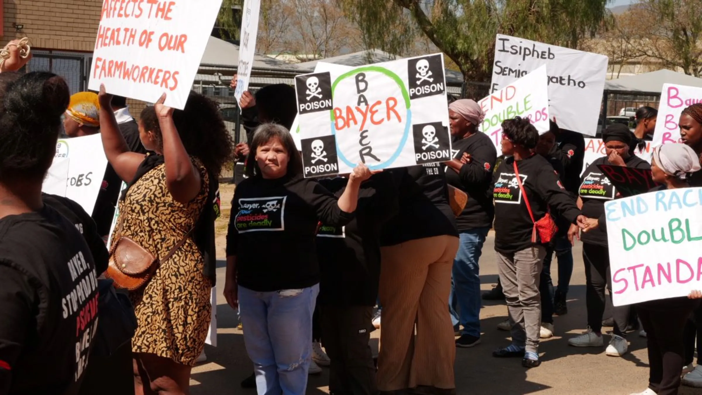 Women farmworkers hold protest signs at a picket against pesticide importer Bayer in Paarl, South Africa, September 8, 2023. Thomson Reuters Foundation/Kim Harrisberg