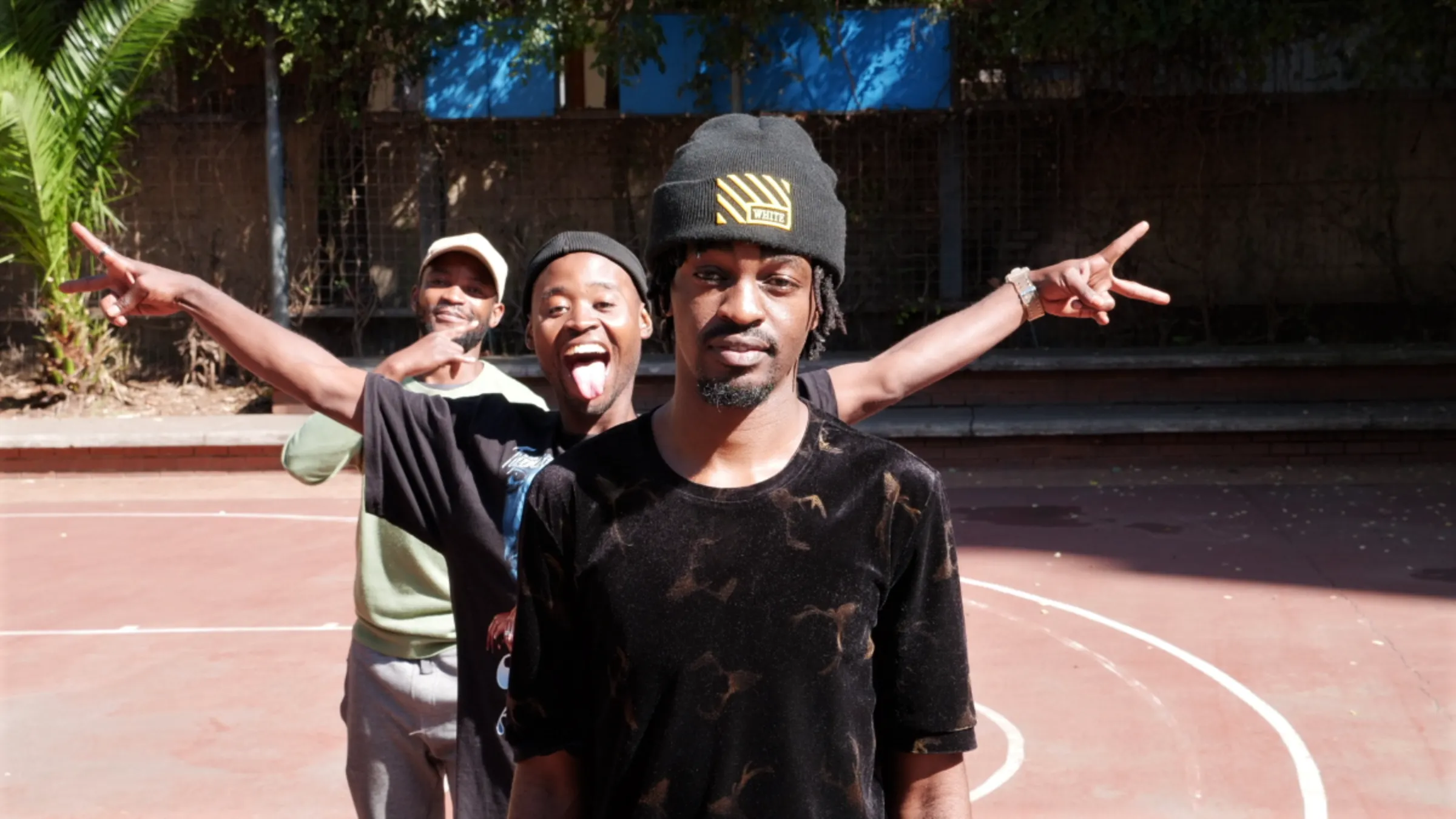 Mawere Taona poses for a photo on the basketball court maintained by Boundless City, while his friends pose and smile behind him in inner-city Johannesburg, South Africa, May 10, 2023. Thomson Reuters Foundation/ Kim Harrisberg