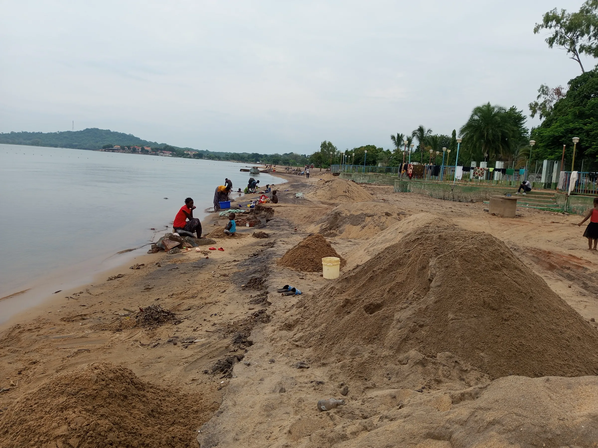 People sitting on the shores of Senga Bay, Salima district, Malawi, where sand mining is common, Feb 28, 2025. Thomson Reuters Foundation/Charles Pensulo