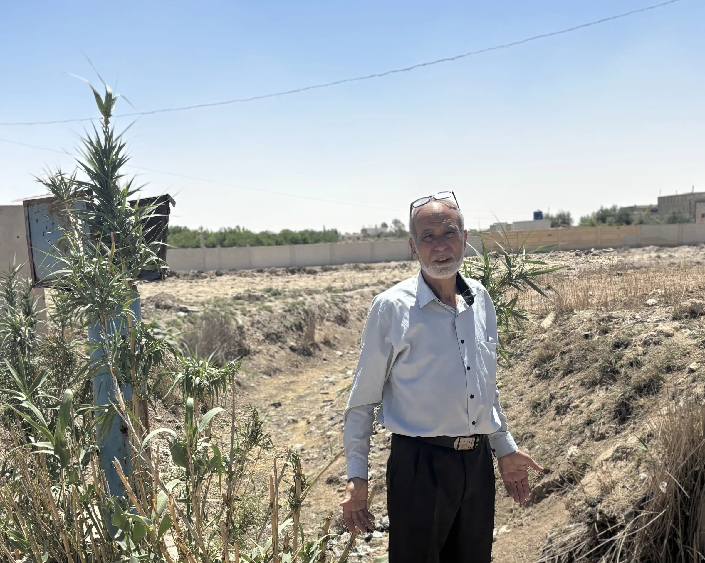 Al- Nashabiyah deputy mayor Mahmoud al-Hobeish stands next to a dry irrigation canal. Al- Nashabiyah, Syria, May 19, 2025. Thomson Reuters Foundation/Nazih Osseiran.
