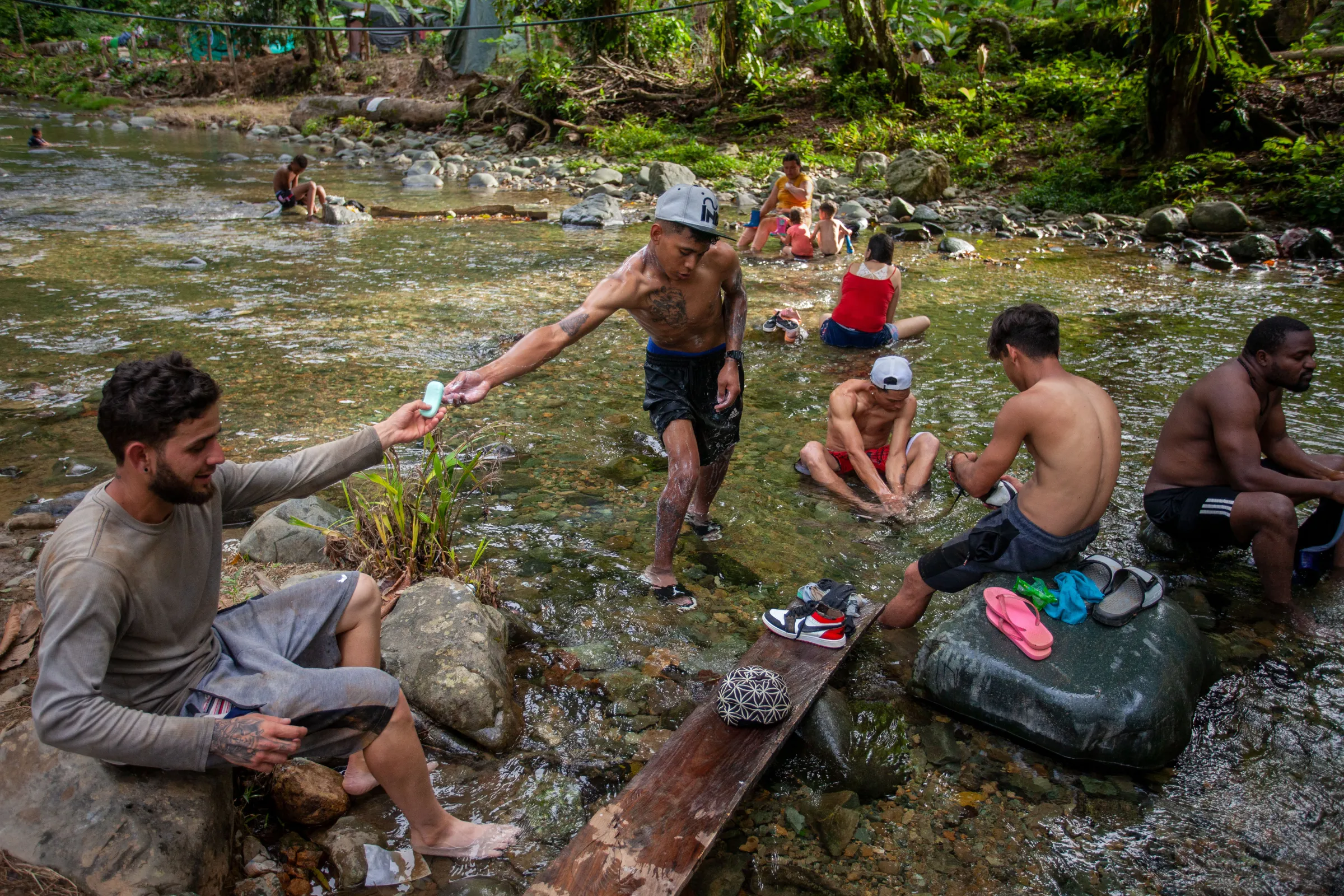 Migrants from Venezuela and African countries take a break and bathe in a stream at the first camping site after a day of trekking in the Colombian jungle in the Darién Gap, Colombia, July 27, 2022. Thomson Reuters Foundation/Fabio Cuttica