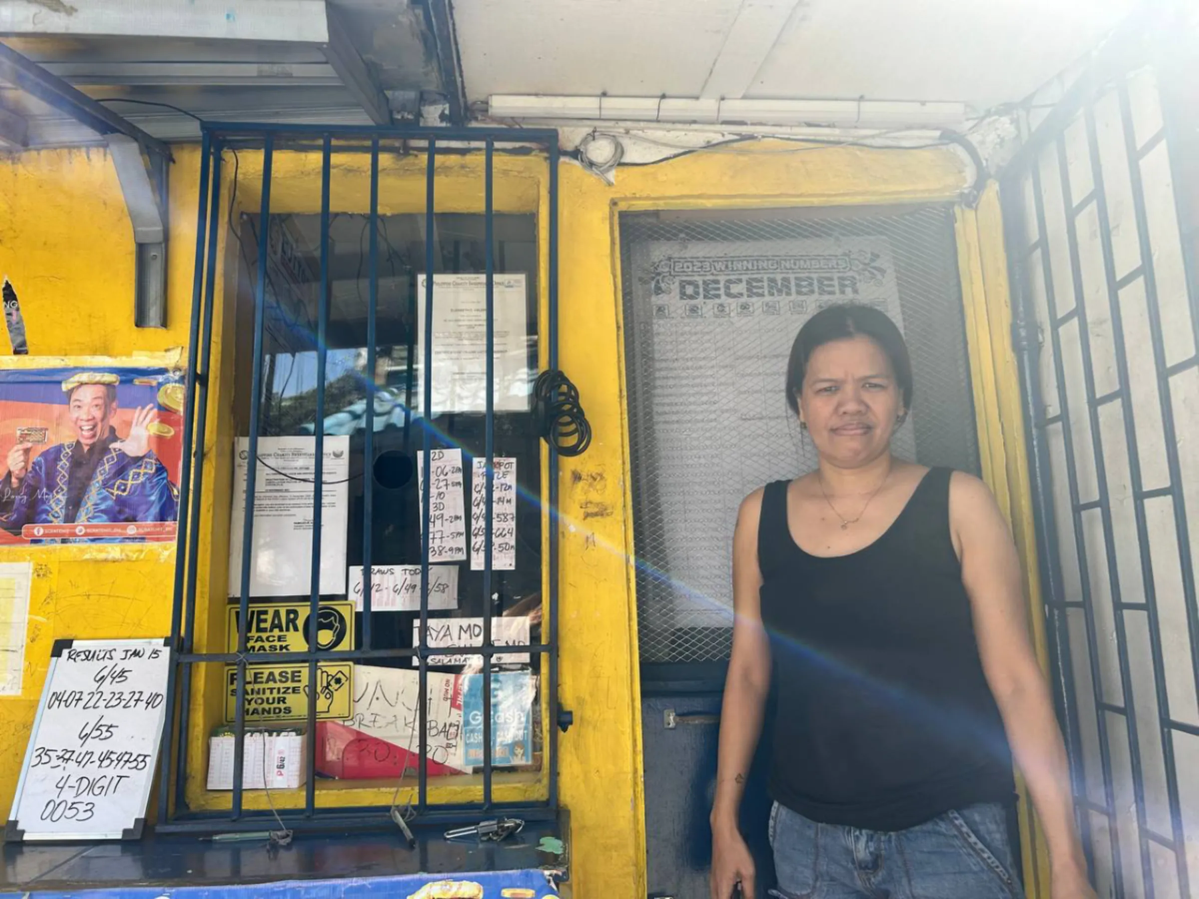 Lucy Ortega stands in front of a lottery outlet where she works part time in Manila, the Philippines, on January 16, 2024. Mariejo Ramos/Thomson Reuters Foundation