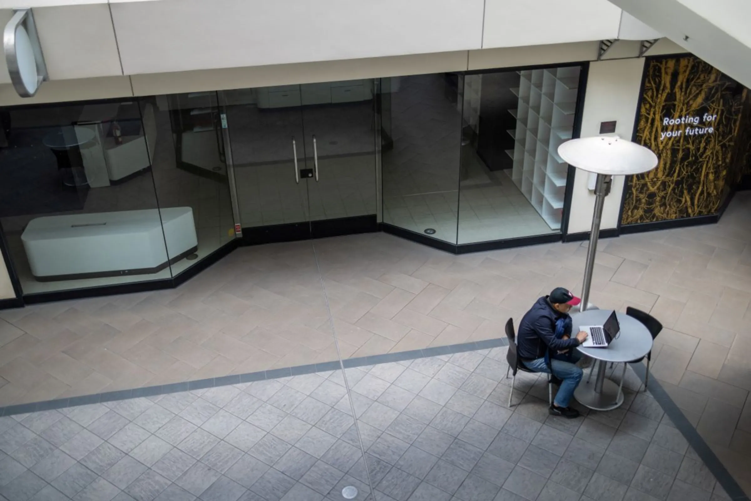 A man looks at his laptop screen at an empty commercial retail area near Union Square in San Francisco, California, U.S., June 7, 2023. REUTERS/Carlos Barria
