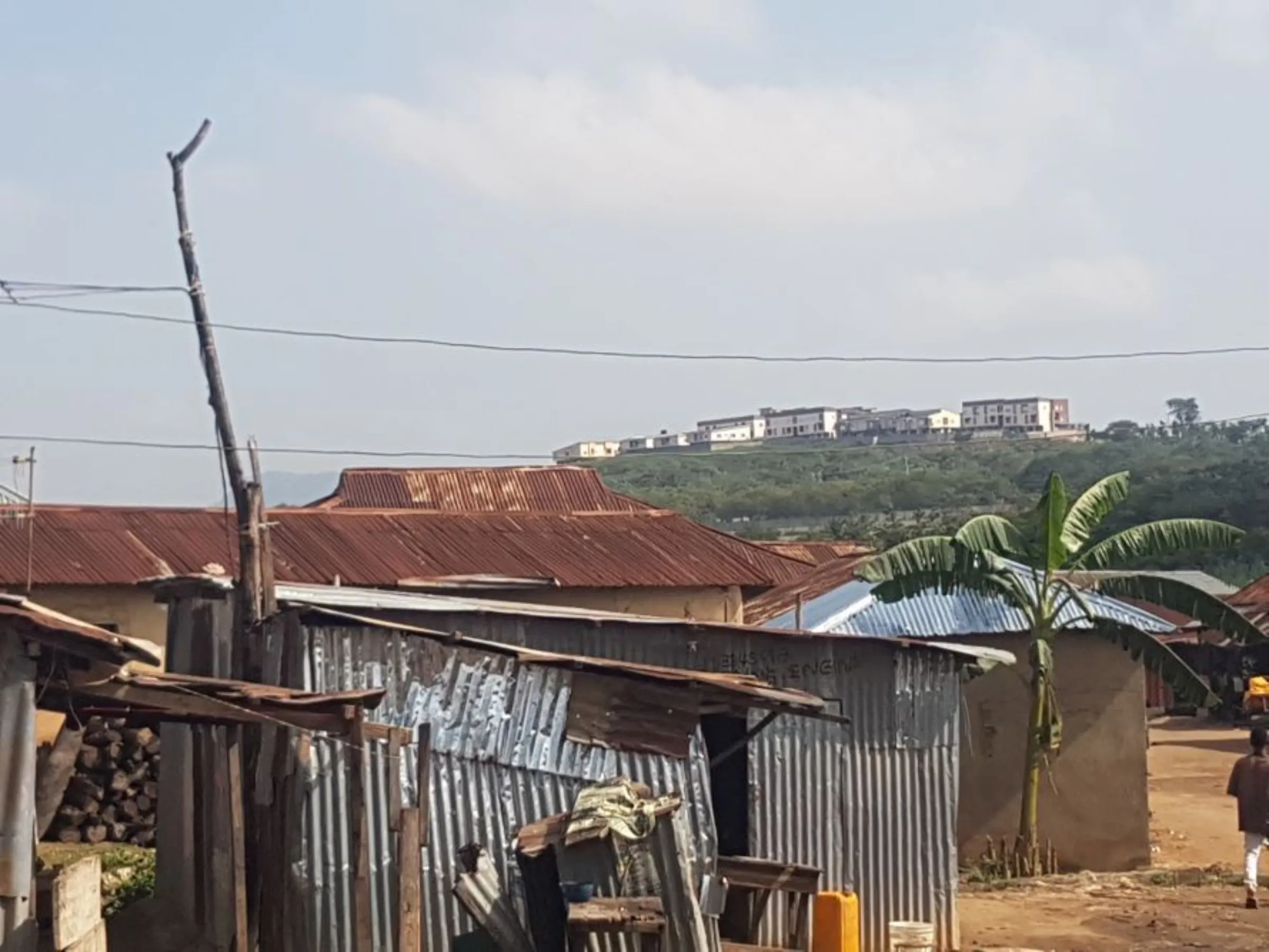 Houses below high-rise apartments in Abuja's Big Bola slum, built with corrugated iron sheets beside dirty water channels in Abuja, Nigeria. October 26, 2022.