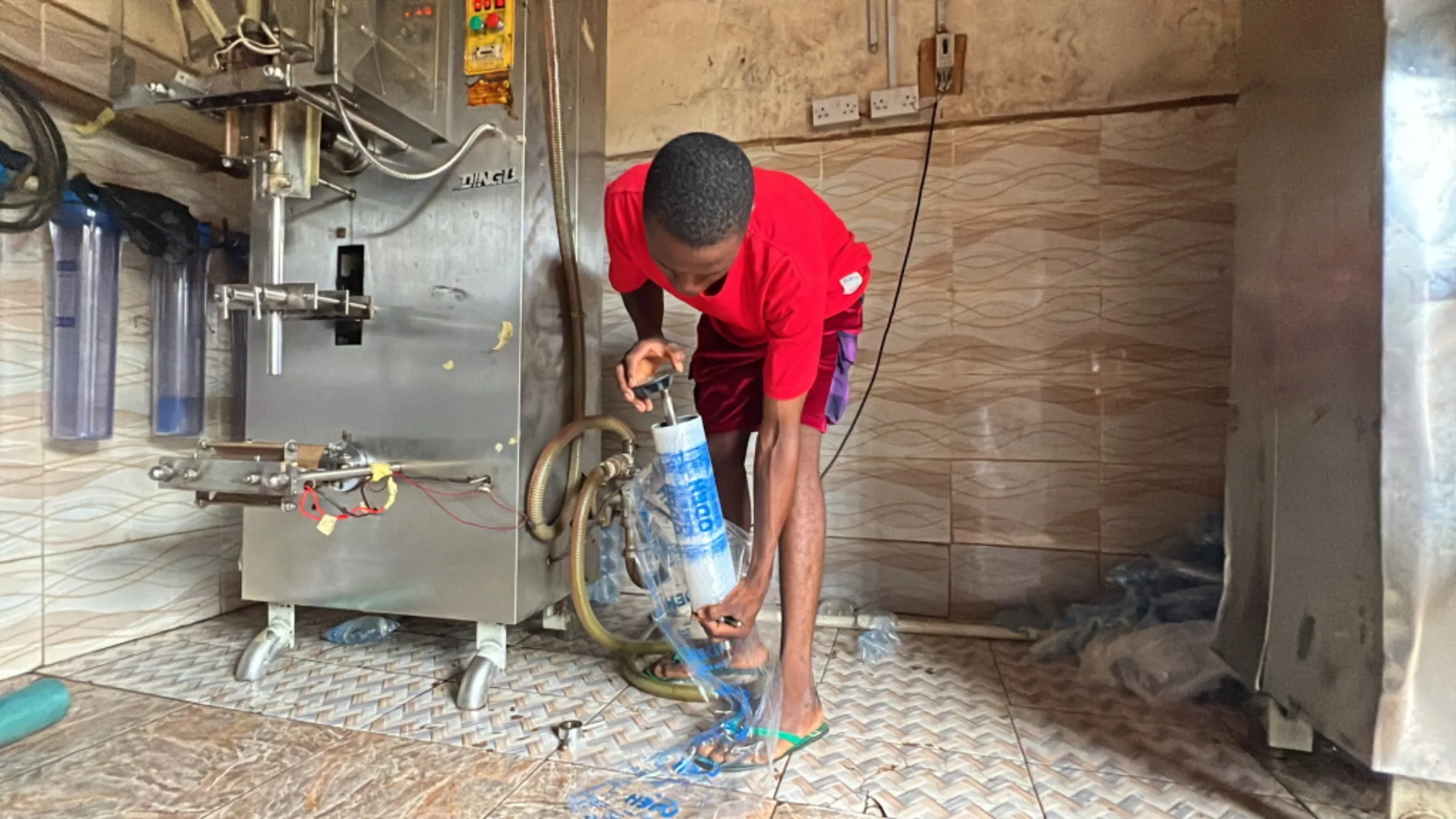 A worker sets up a polythene roller for a solar-powered drinking-water packaging machine in Rukubi, Nasarawa, Nigeria, September 27, 2022. Thomson Reuters Foundation/Afolabi Sotunde