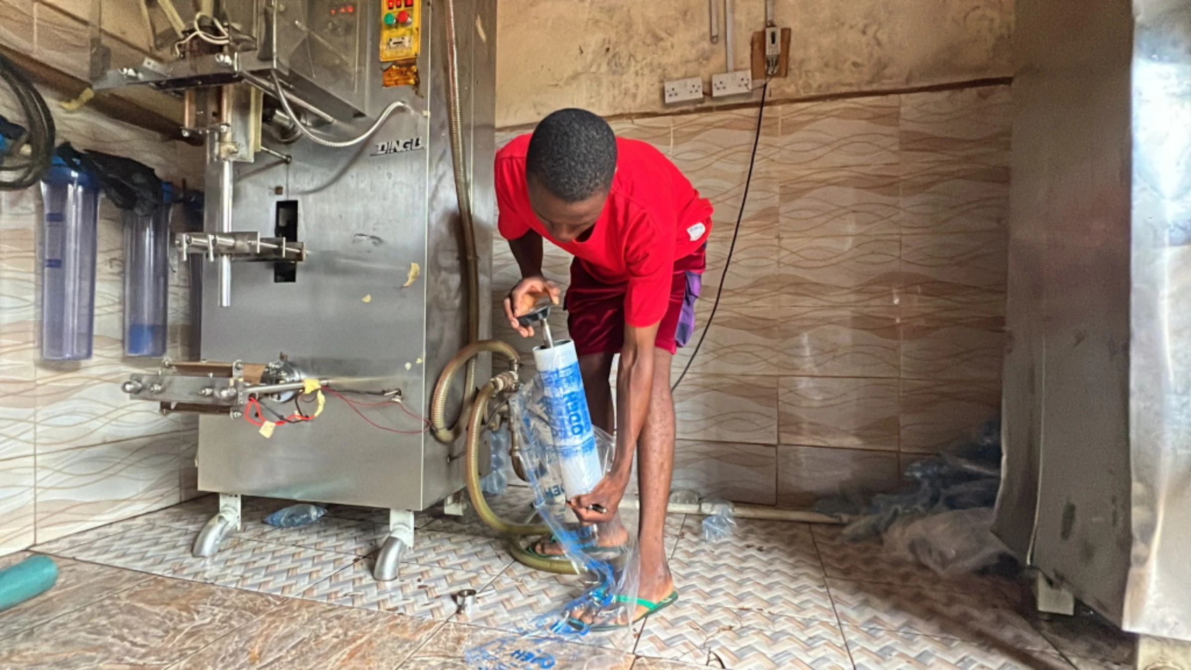 A worker sets up a polythene roller for a solar-powered drinking-water packaging machine in Rukubi, Nasarawa, Nigeria, September 27, 2022. Thomson Reuters Foundation/Afolabi Sotunde