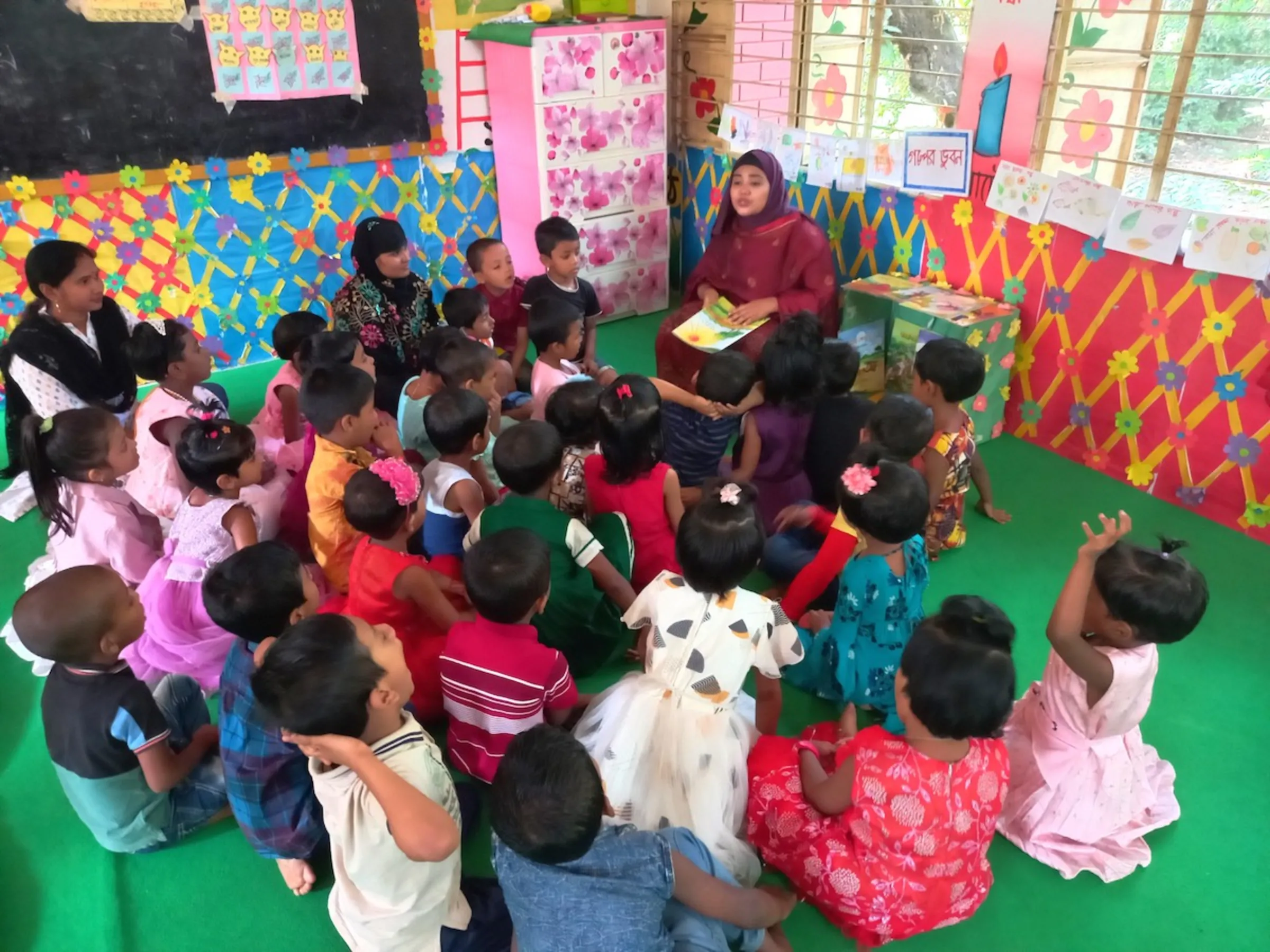 Children aged between three and five listen to a teacher at a green play lab supported by development organisation BRAC at Brahmangaon, Gazipur, Bangladesh, November 11, 2023