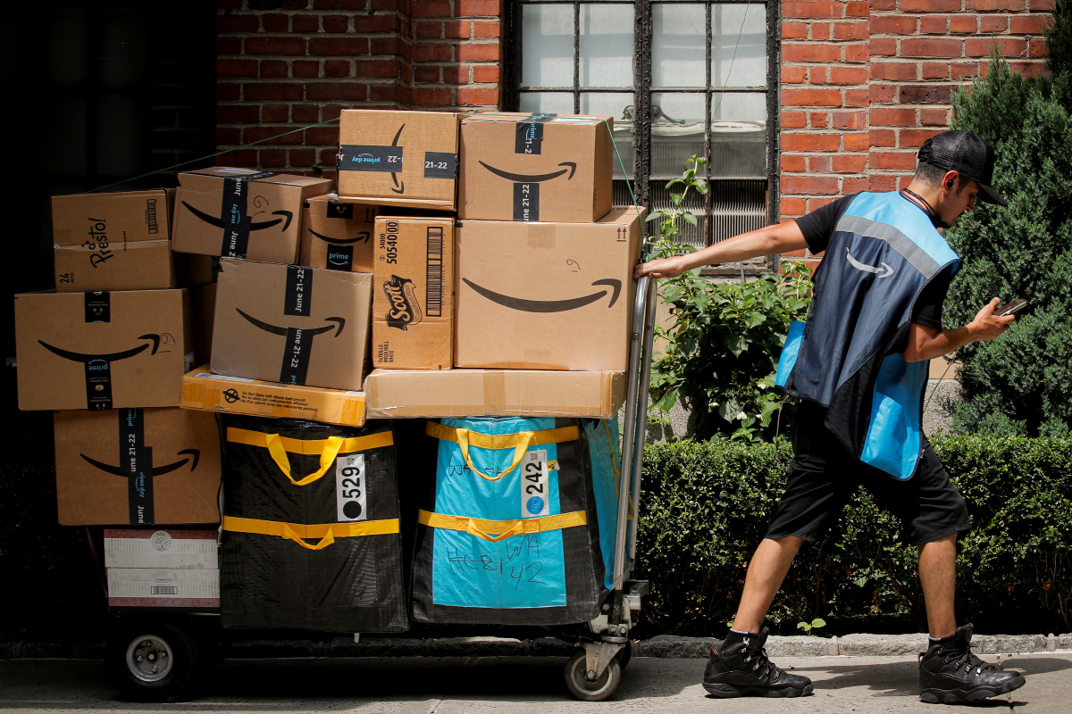 An Amazon delivery worker pulls a delivery cart full of packages during its annual Prime Day promotion in New York City, U.S., June 21, 2021. REUTERS/Brendan McDermid