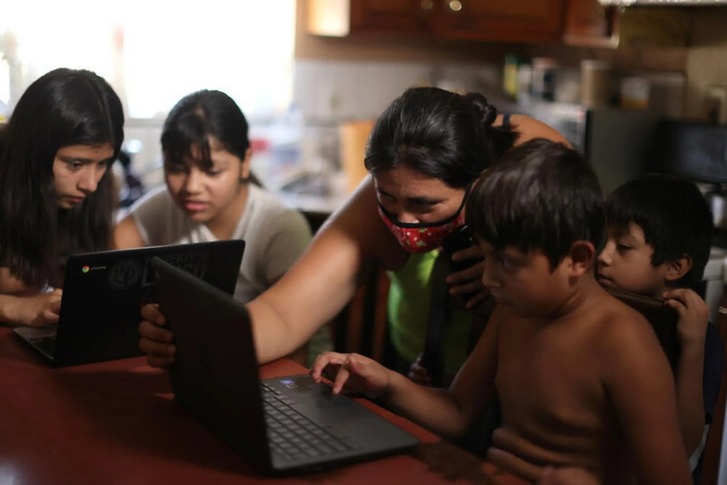 Los Angeles Unified School District (LAUSD) students Keiley Flores, 13, Andrea Ramos, 10, and Alexander Ramos, 8, work on school-issued computers with unreliable internet connectivity, as their mother Anely Solis, 32, and their brother Enrique Ramos, 5, look on, during the global outbreak of the coronavirus disease , at their home in Los Angeles, California, U.S., August 18, 2020