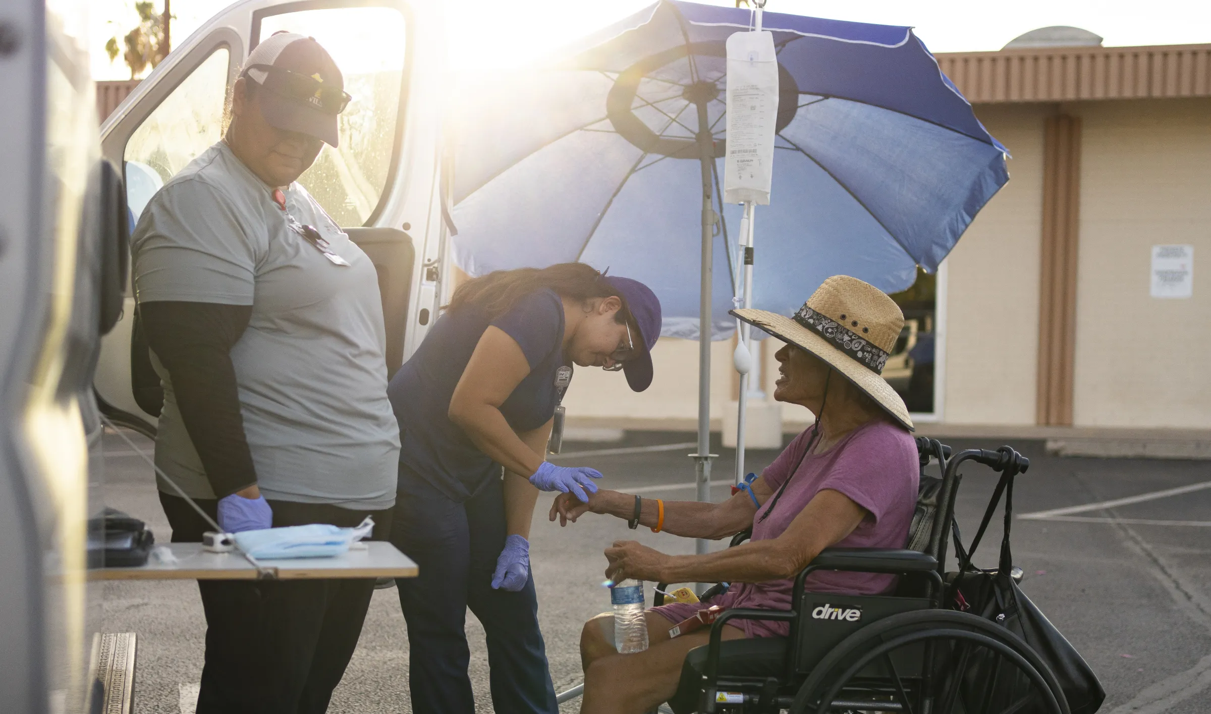 From left, Brenda Madril and Perla Puebla from Circle the City prepare Maurajean Bunn for an emergency IV. July 15, 2024. Thomson Reuters Foundation/Rebecca Noble