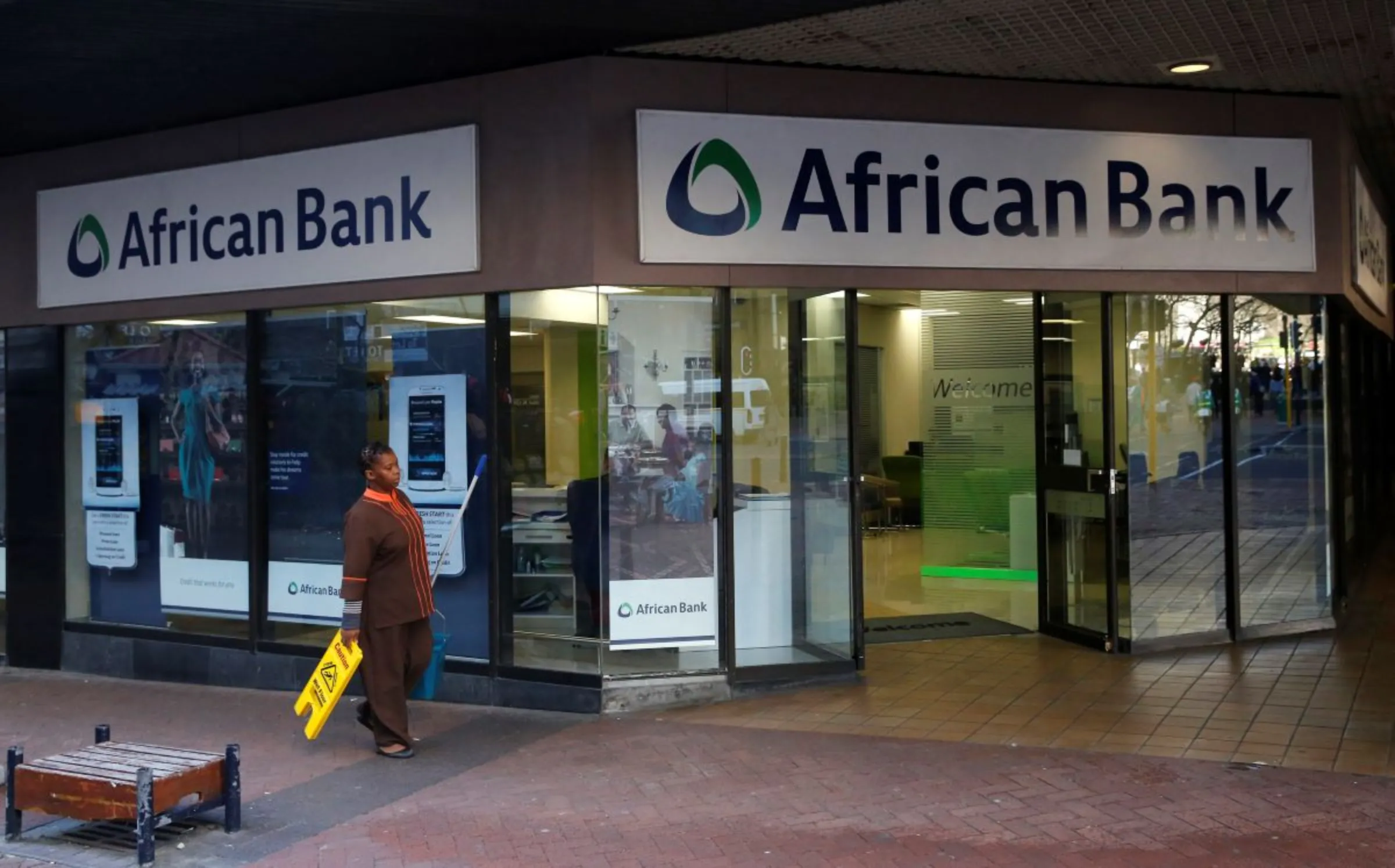 A cleaner walks past a branch of African Bank in Cape Town August 8, 2014